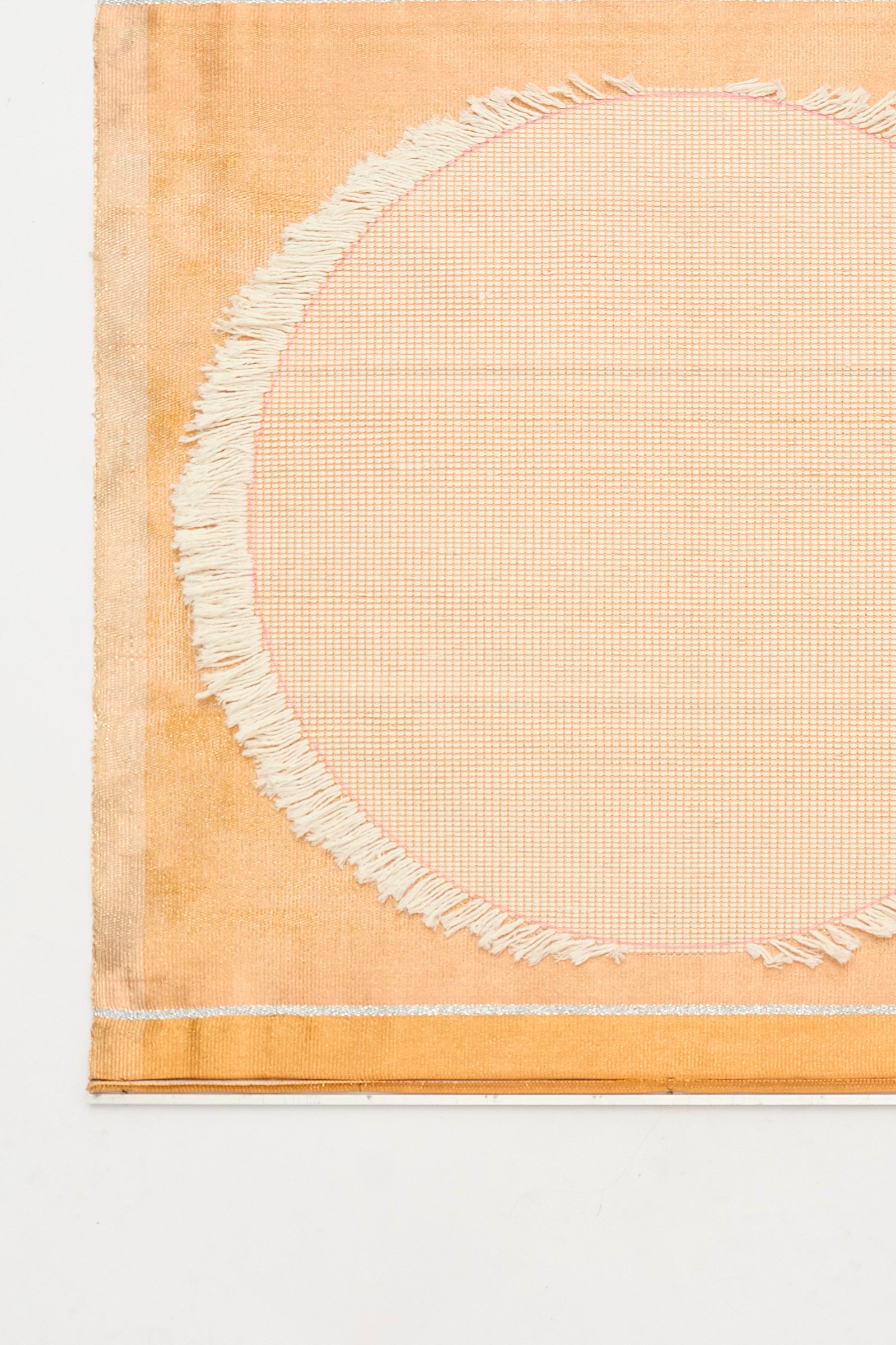 White Moon Weaving by Justine Ashbee is a handmade rectangular mat featuring a central circular pattern, frayed edge details, and a light orange-beige palette—crafted in the UK.