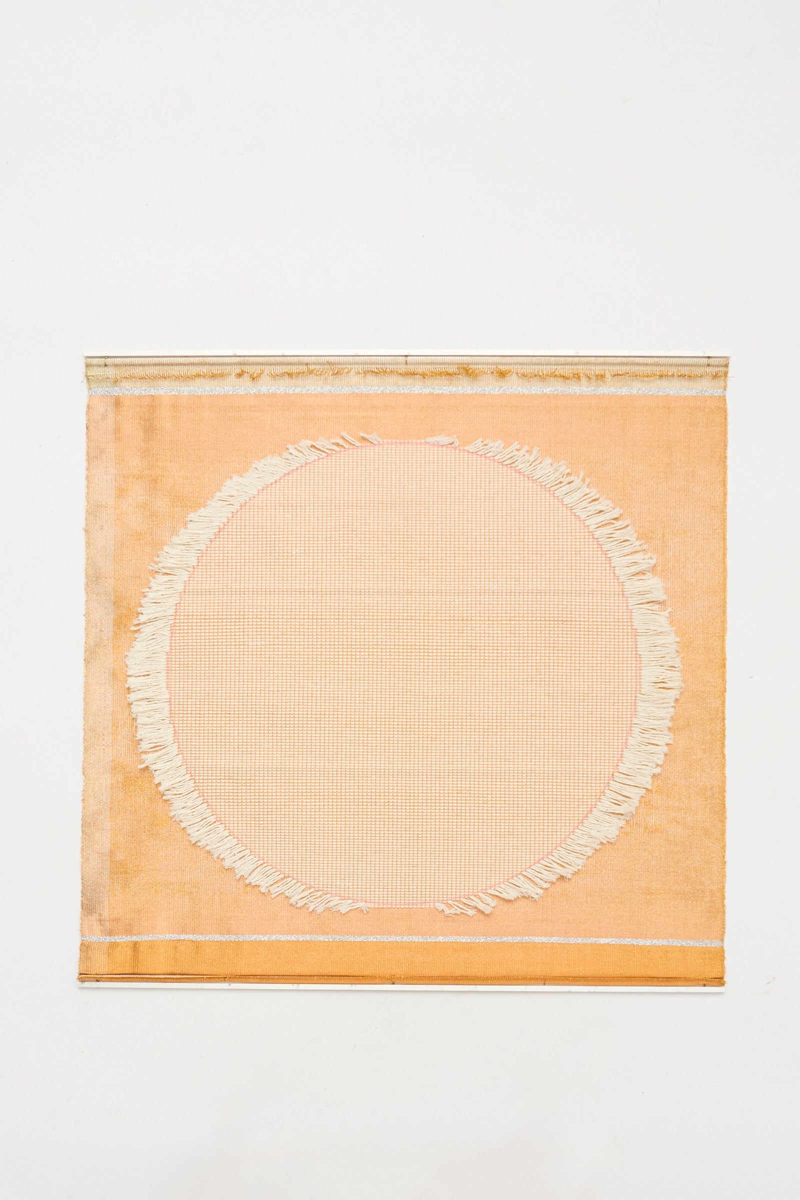 The White Moon Weaving by Justine Ashbee is a handmade square orange textile from the UK, showcasing a large off-white fringed circle in the center, displayed on a plain white background.