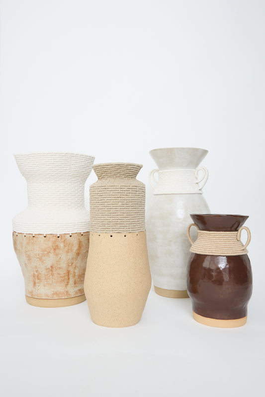 A collection of five textured, handcrafted ceramic vases of varying designs and neutral tones from Karen Tinney displayed against a white background.
