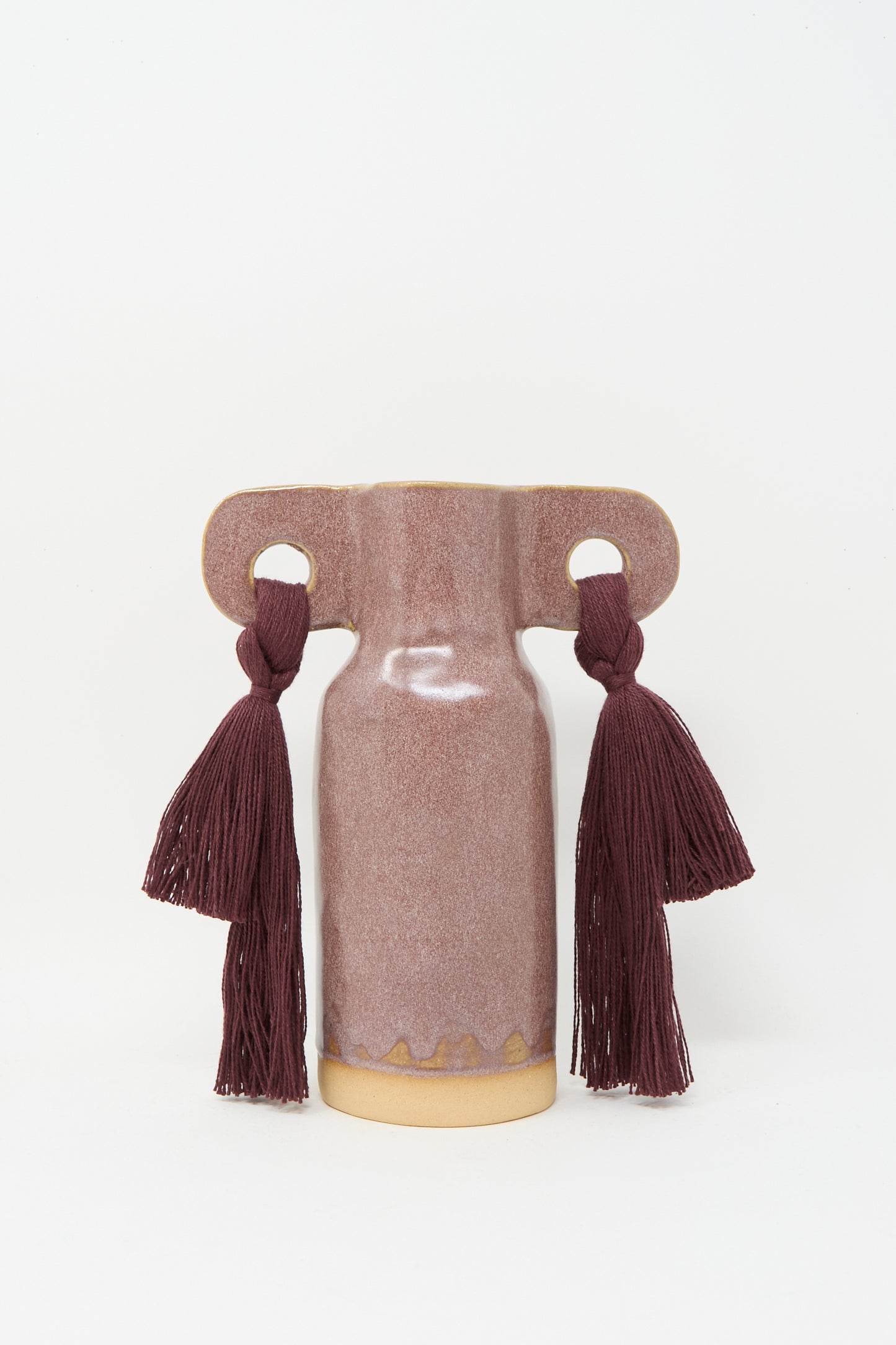 Vase #606 in Burgundy by Karen Tinney is a petite, handmade stoneware vase with a matte mauve finish, wide horizontal handles, and two dark burgundy tassels on each side.