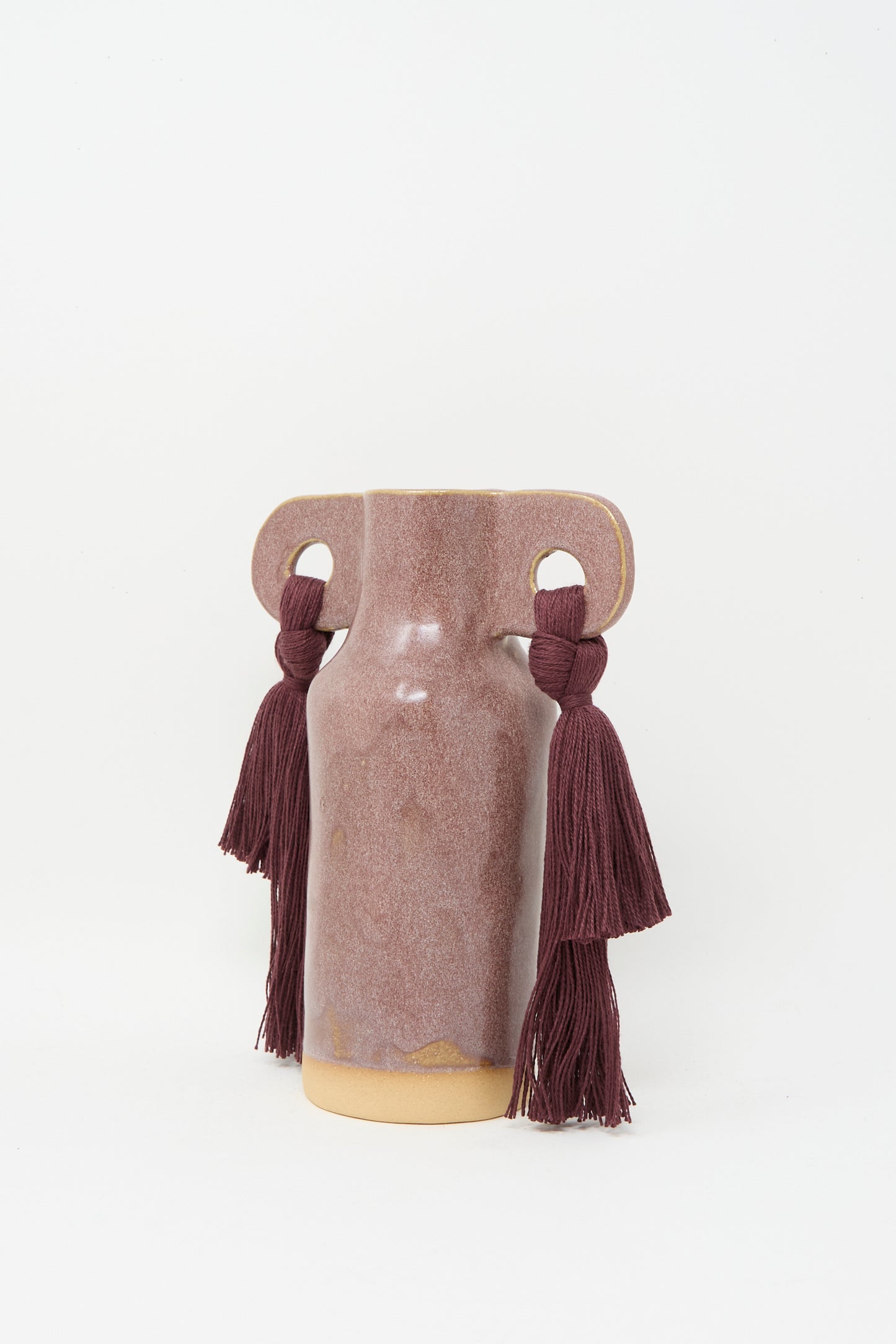 Karen Tinney’s Vase #606 in Burgundy is a petite mauve ceramic vase with dual handles, each decorated with a burgundy tassel, shown against a plain white background.