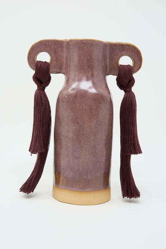 A Karen Tinney stoneware Vase #606 in Burgundy with two handles, resembling the shape of a classical amphora, adorned with burgundy tassels.
