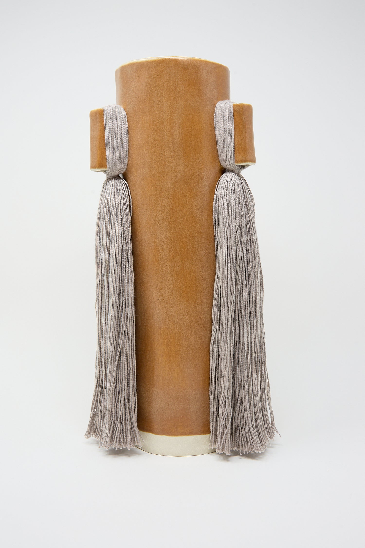 Handcrafted Karen Tinney velvet cylindrical bolster pillow with tassels on a white background.
