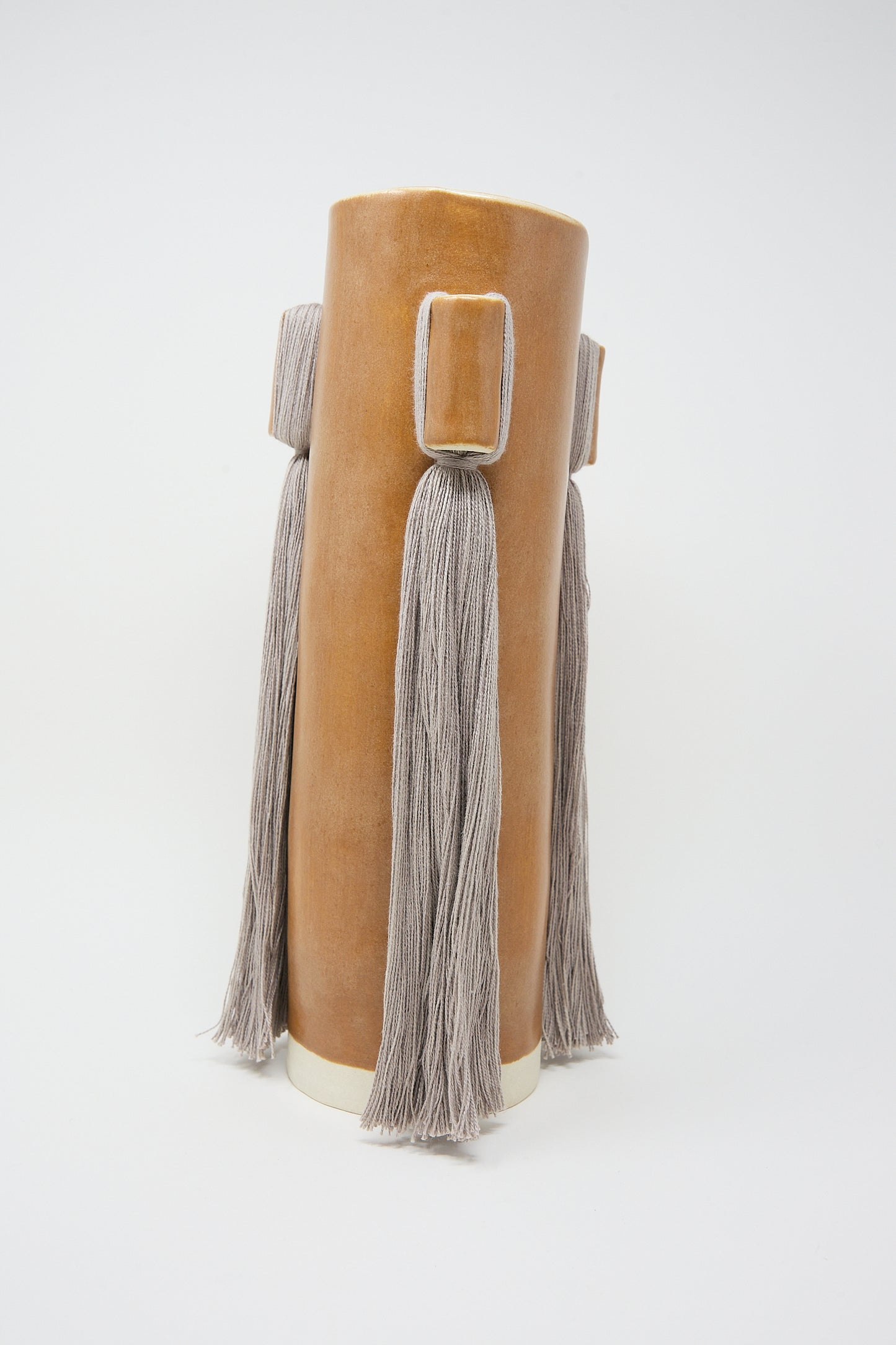 Handcrafted Vase #607 in Brown stoneware vase with tassel details by Karen Tinney on a white background.