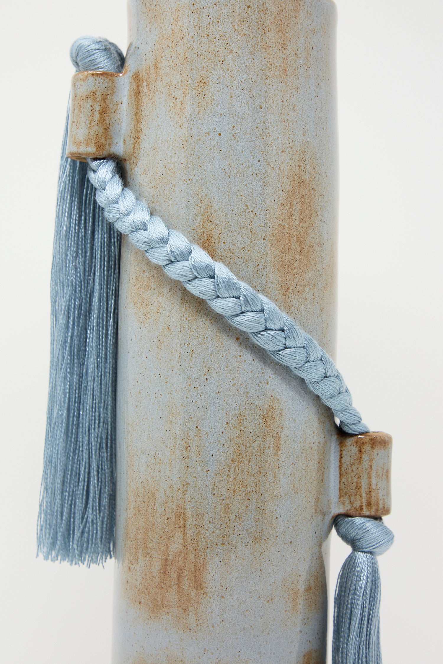 Blue tassel and cord wrapped around a weathered cylindrical Karen Tinney Vase #695 in Blue.