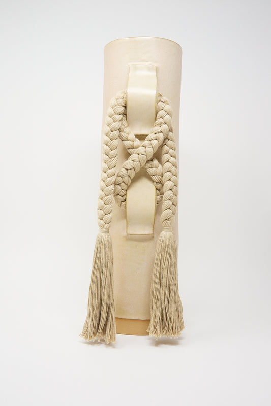 A mannequin torso displaying a handcrafted cream-colored knitted scarf with thick braids and tassels by Karen Tinney's Vase #696 in Tan.
