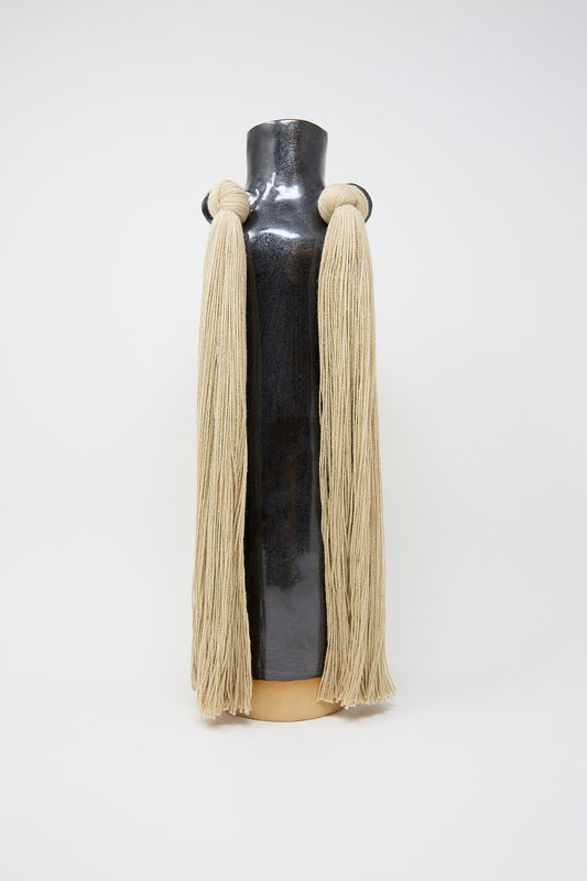 Decorative Karen Tinney stoneware Vase #703 in Black with tassel embellishments against a white background.