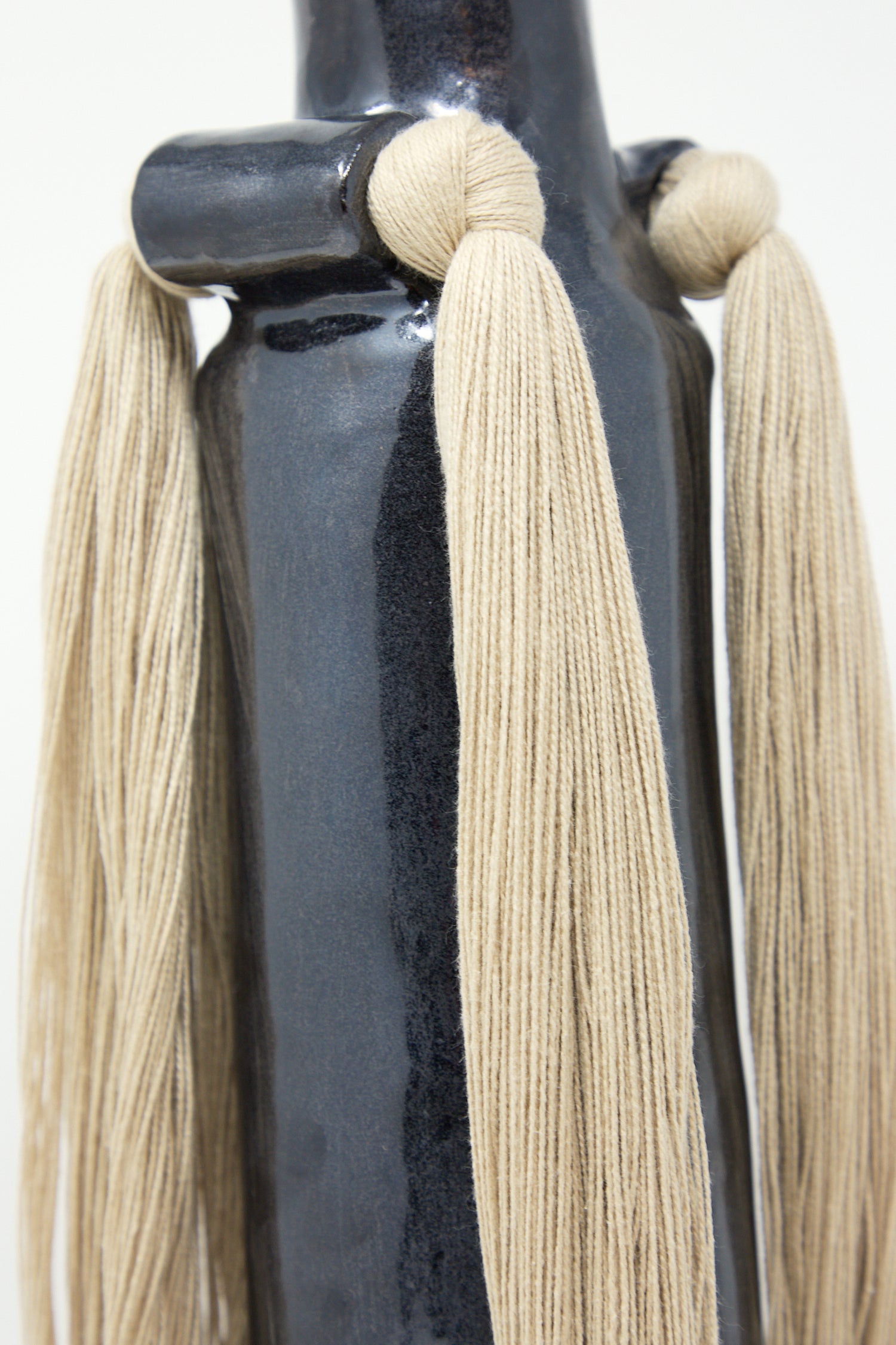Beige tassels attached to a Karen Tinney Vase #703 in Black.
