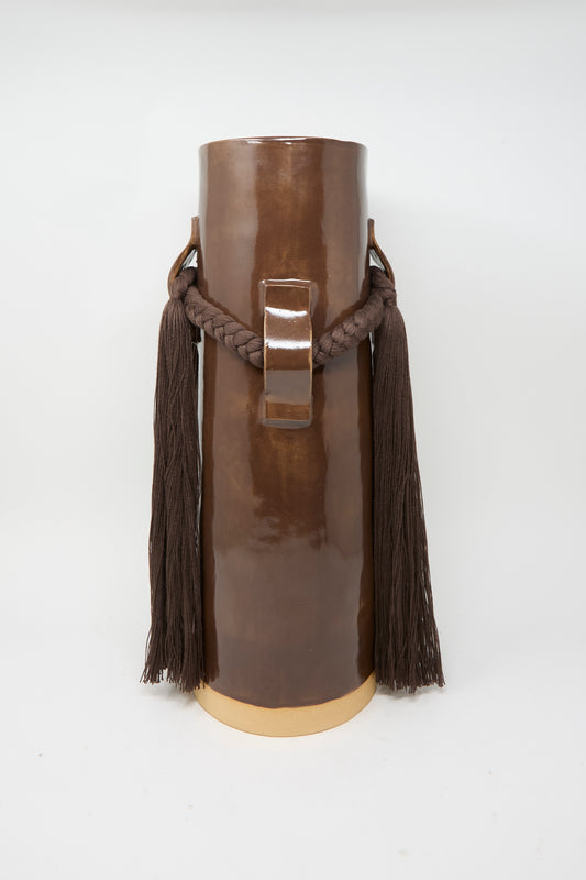 Vase #800 in Brown by Karen Tinney features a tall, glossy brown glazed form with a central handle, thick braided rope adorned with long tassels on each side, and stands on a cream-colored base—a striking example of the brand’s Vermont pottery craftsmanship.