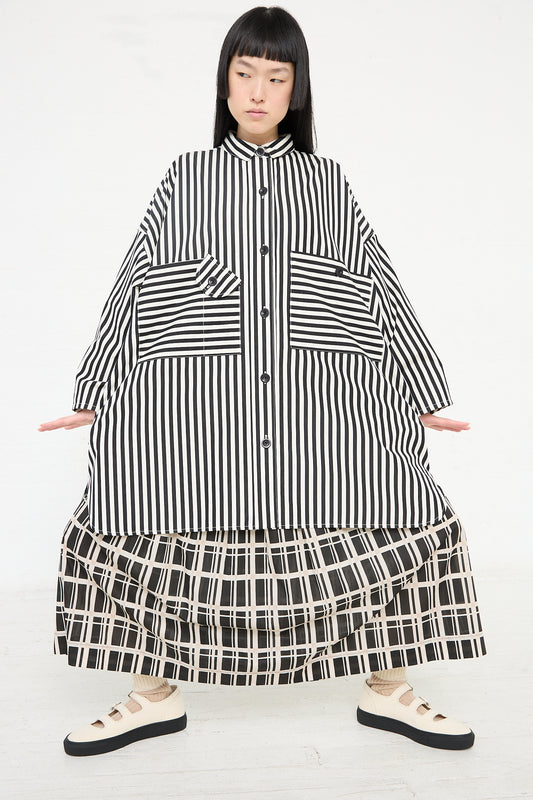 Woman posing in a Cotton Poplin Oversized Smock Dress in Stripe by KasMaria with layered patterns, offering a relaxed fit.
