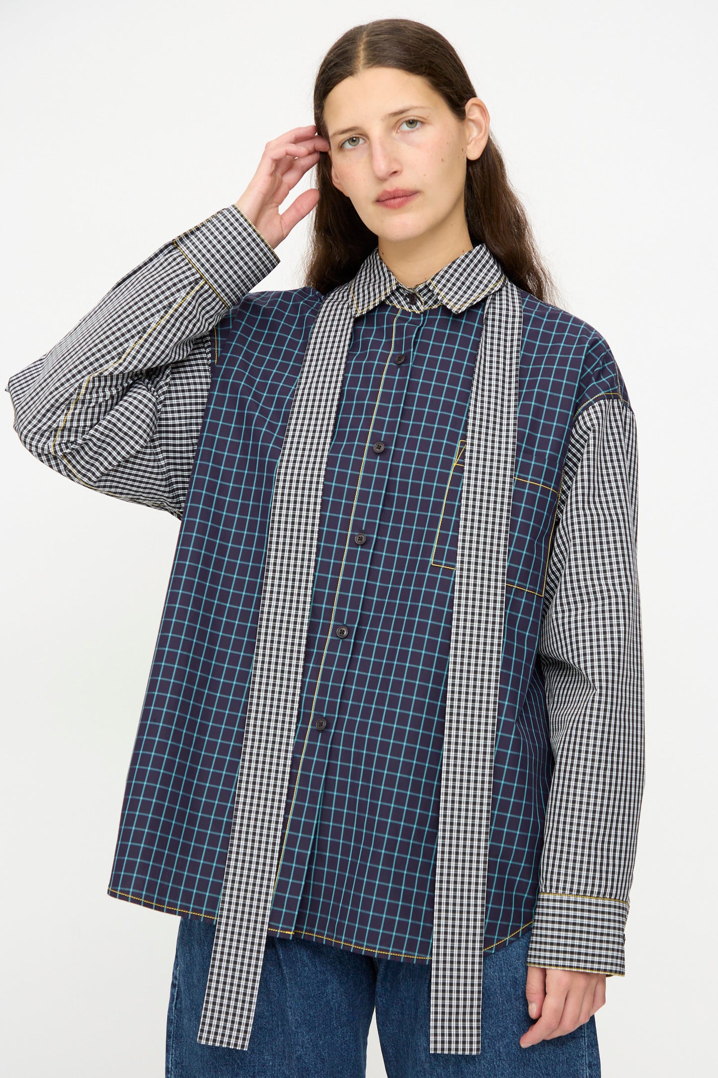 A person wears the KasMaria Cotton Shirt with Tie in Check Combo—a relaxed fit Italian cotton button-down with long scarf-like extensions—paired with blue jeans, standing against a plain light background.