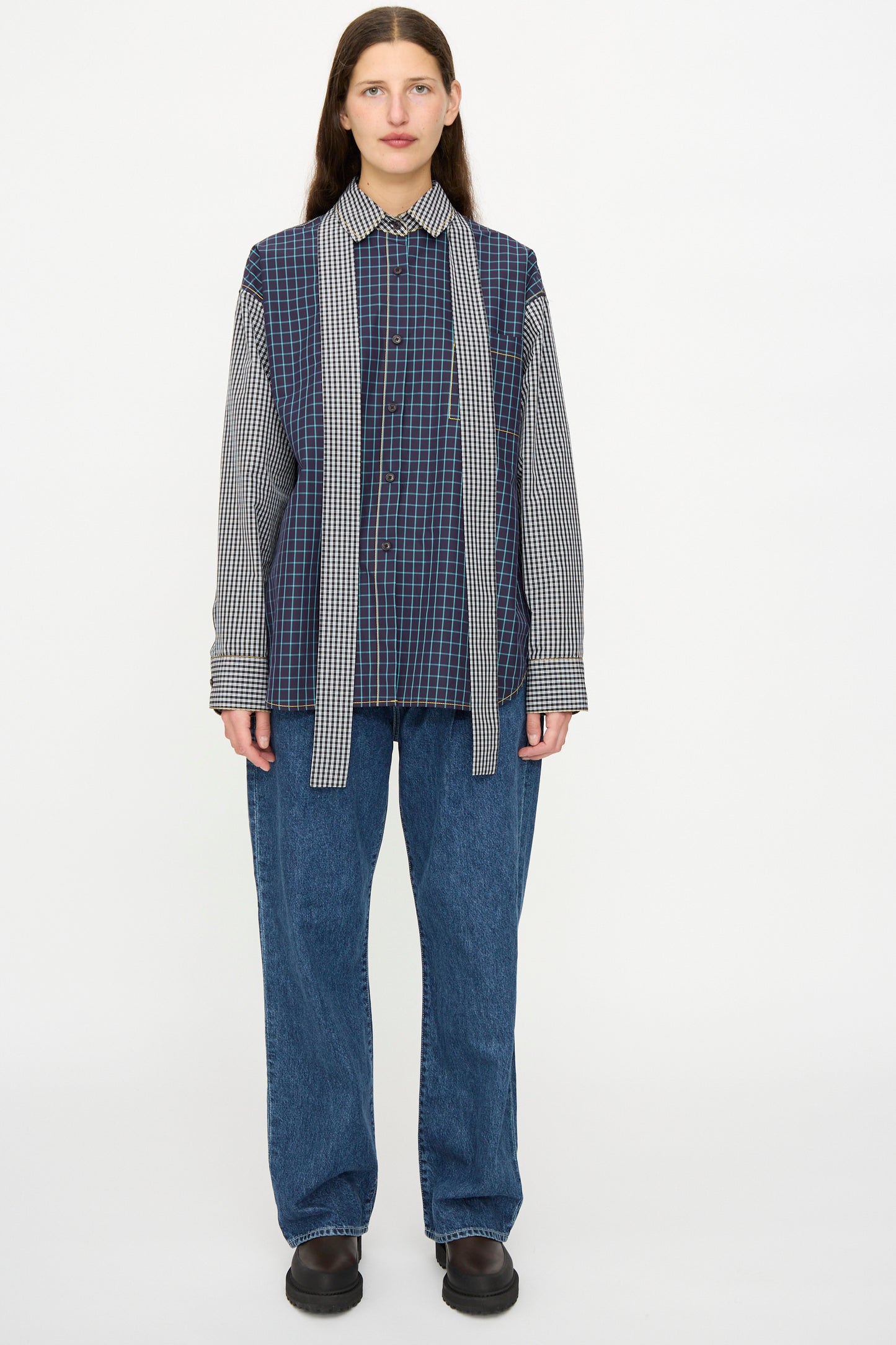 A person faces forward wearing the KasMaria Cotton Shirt with Tie in Check Combo—a relaxed fit blue plaid button down with scarf-like panels—paired with blue jeans and black shoes against a plain white background.