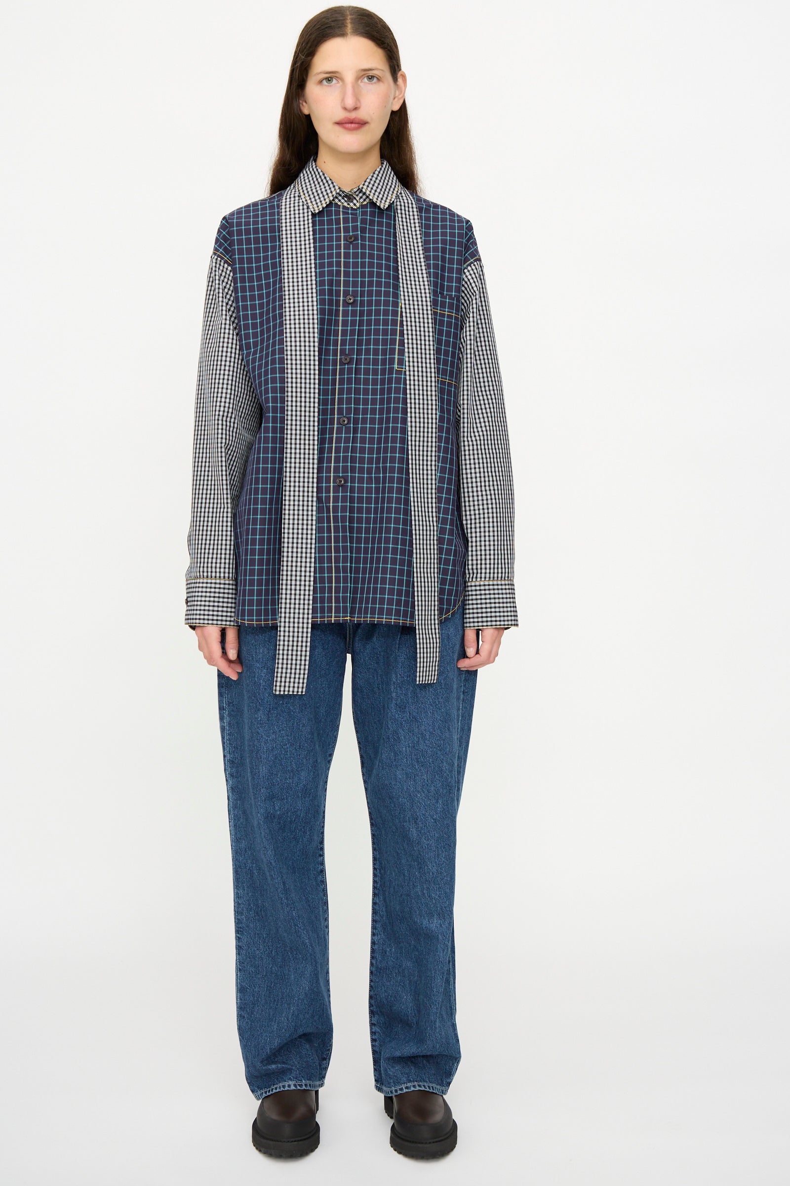 A person faces forward wearing the KasMaria Cotton Shirt with Tie in Check Combo—a relaxed fit blue plaid button down with scarf-like panels—paired with blue jeans and black shoes against a plain white background.