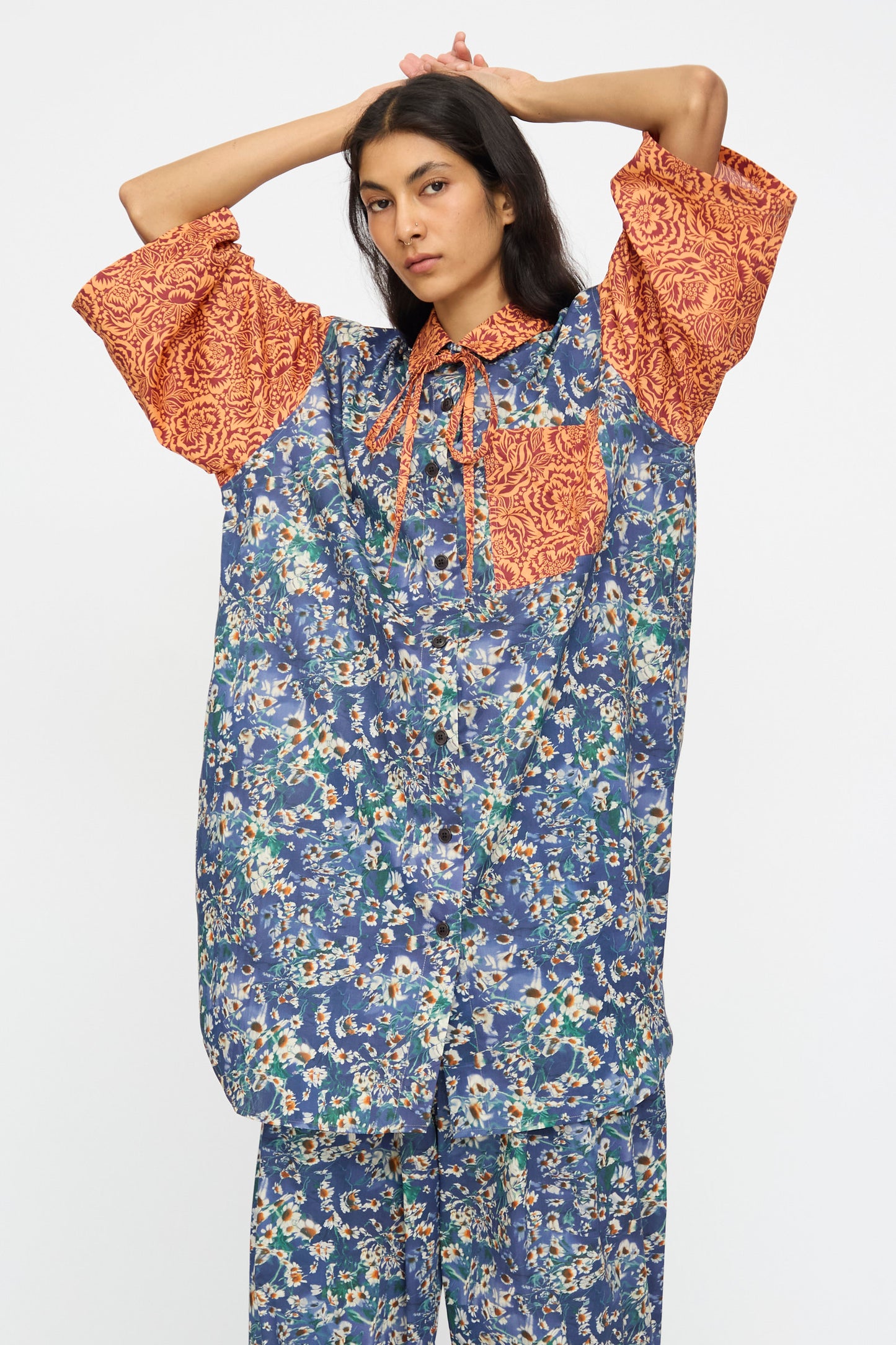 A model wears the KasMaria Liberty Floral Oversized Shirtdress in Blue and Orange, featuring contrasting patterns, against a plain white background.