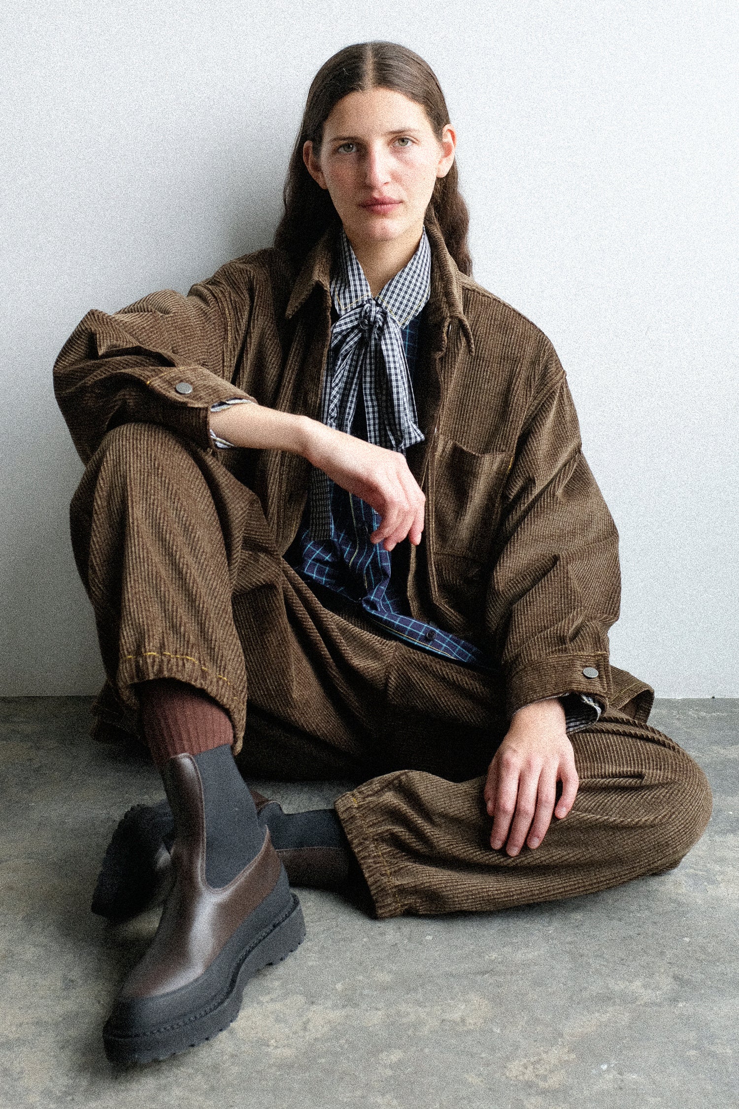 A woman sitting on the ground wearing pieces from KasMaria's PS26 collection.