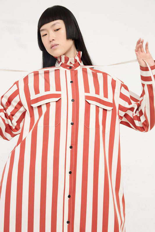A woman models a KasMaria Cotton Poplin Ruffle Neck Shirt Dress in Stripe adorned with playful ruffle details.