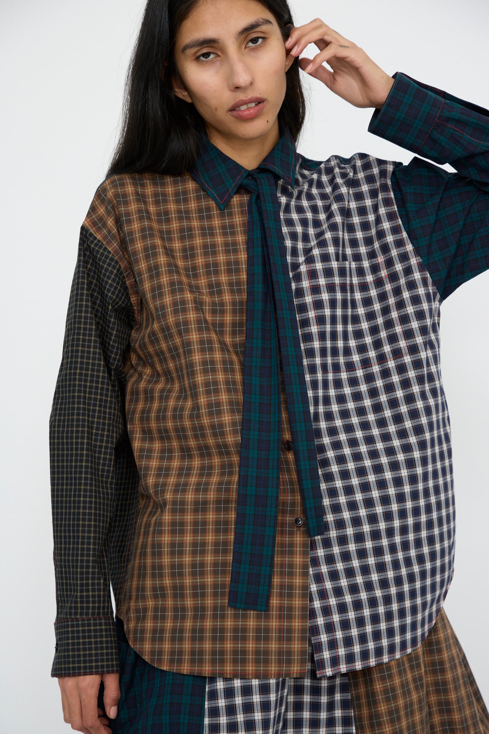 A person wearing the Heavy Poplin Oversized Shirt with Tie in Mixed Plaid by KasMaria poses against a plain background, their outfit fastened with Italian Corozo buttons.