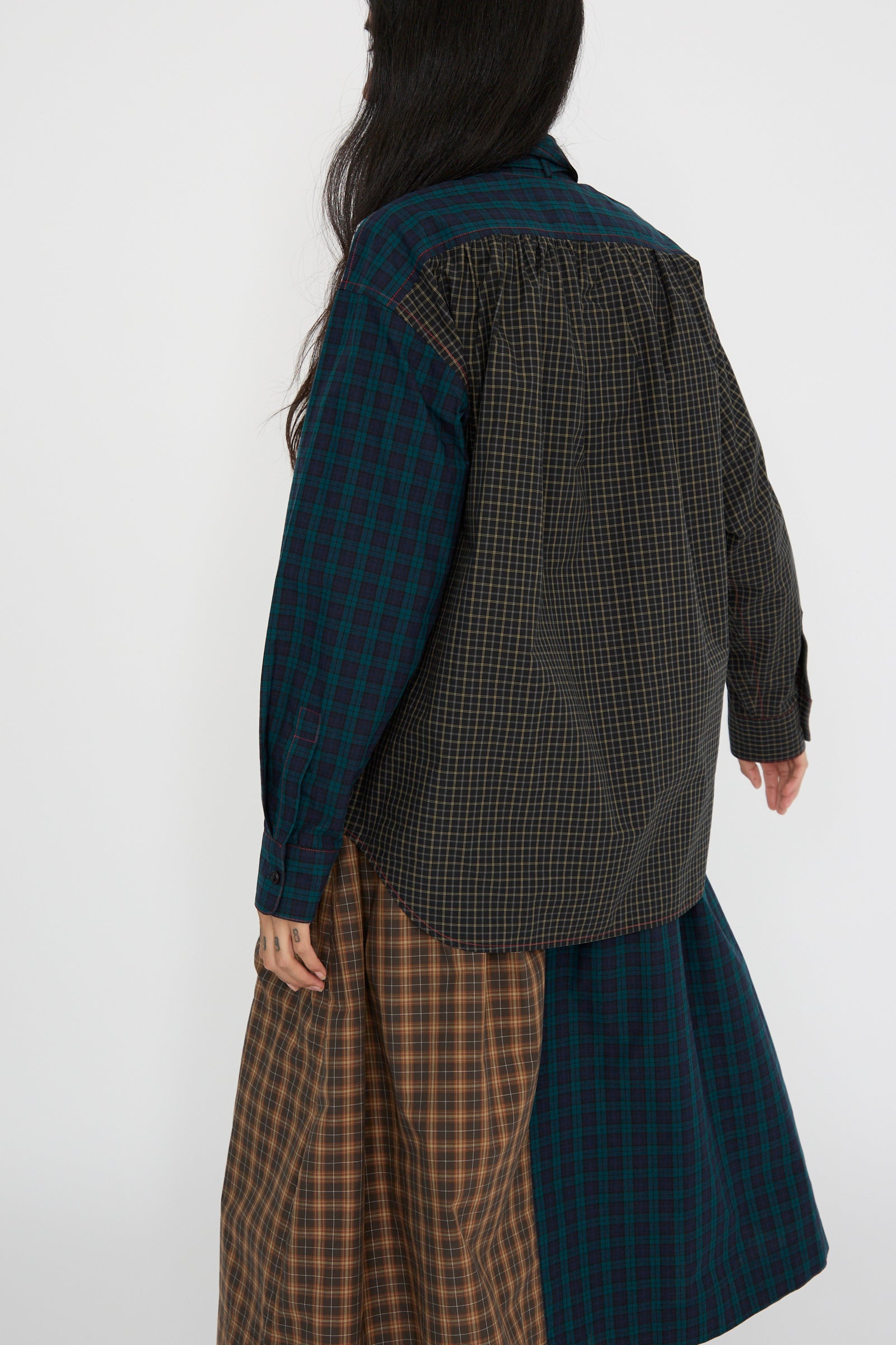 A person with long dark hair, turned to the back is wearing an oversized shirt with a mixed plaid design made from Japanese cotton poplin by KasMaria.