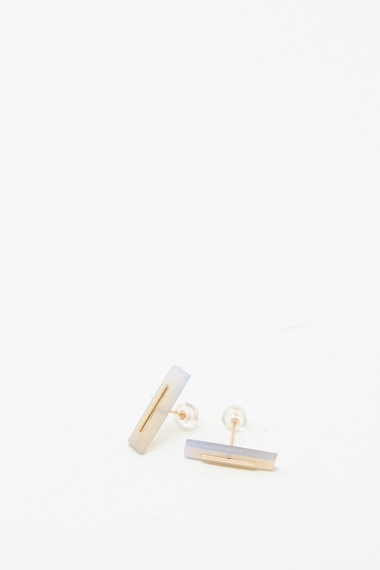 The 14K Yellow Gold Long Staple Studs, featuring a sleek bar design with 5mm Violet Chalcedony, are elegantly displayed against a plain white background. These minimalist earrings are crafted by Kathleen Whitaker.