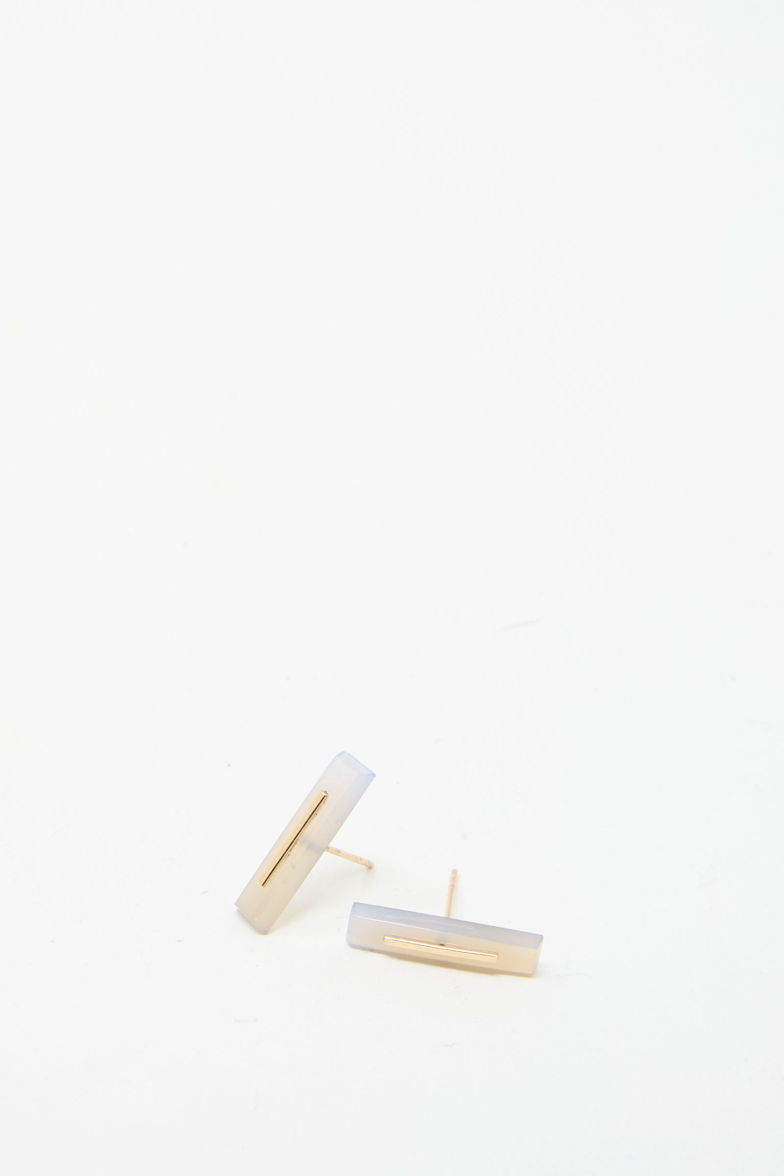 Two 14K yellow gold rectangular earrings styled with a minimalist touch are set against a plain white background. Crafted by Kathleen Whitaker, these long staple stud earrings in violet chalcedony offer simple elegance, making them a timeless accessory for any occasion.