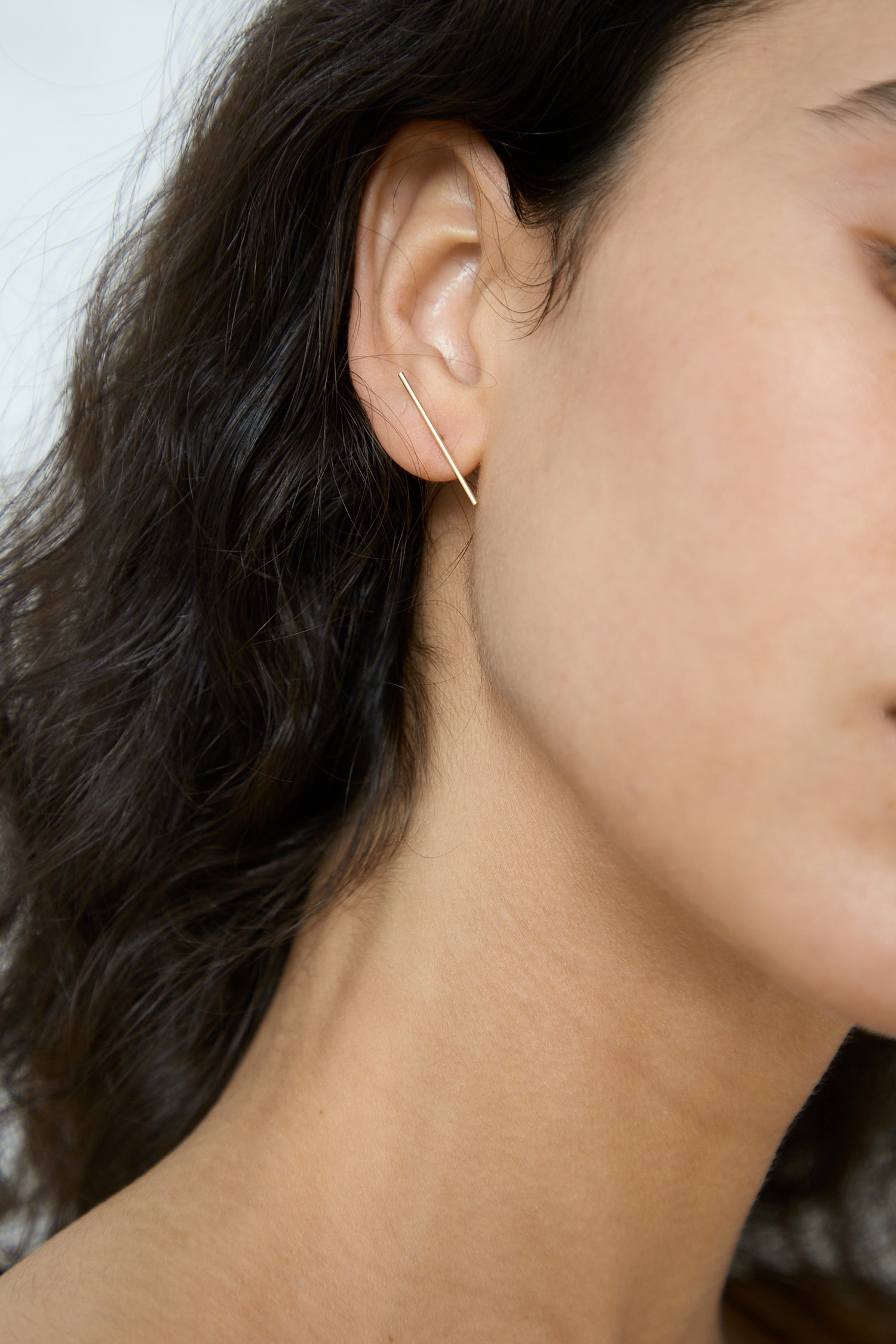 A close up of a woman's ear with Kathleen Whitaker Stick Stud 1" Single Earring in 14K Yellow Gold earrings.