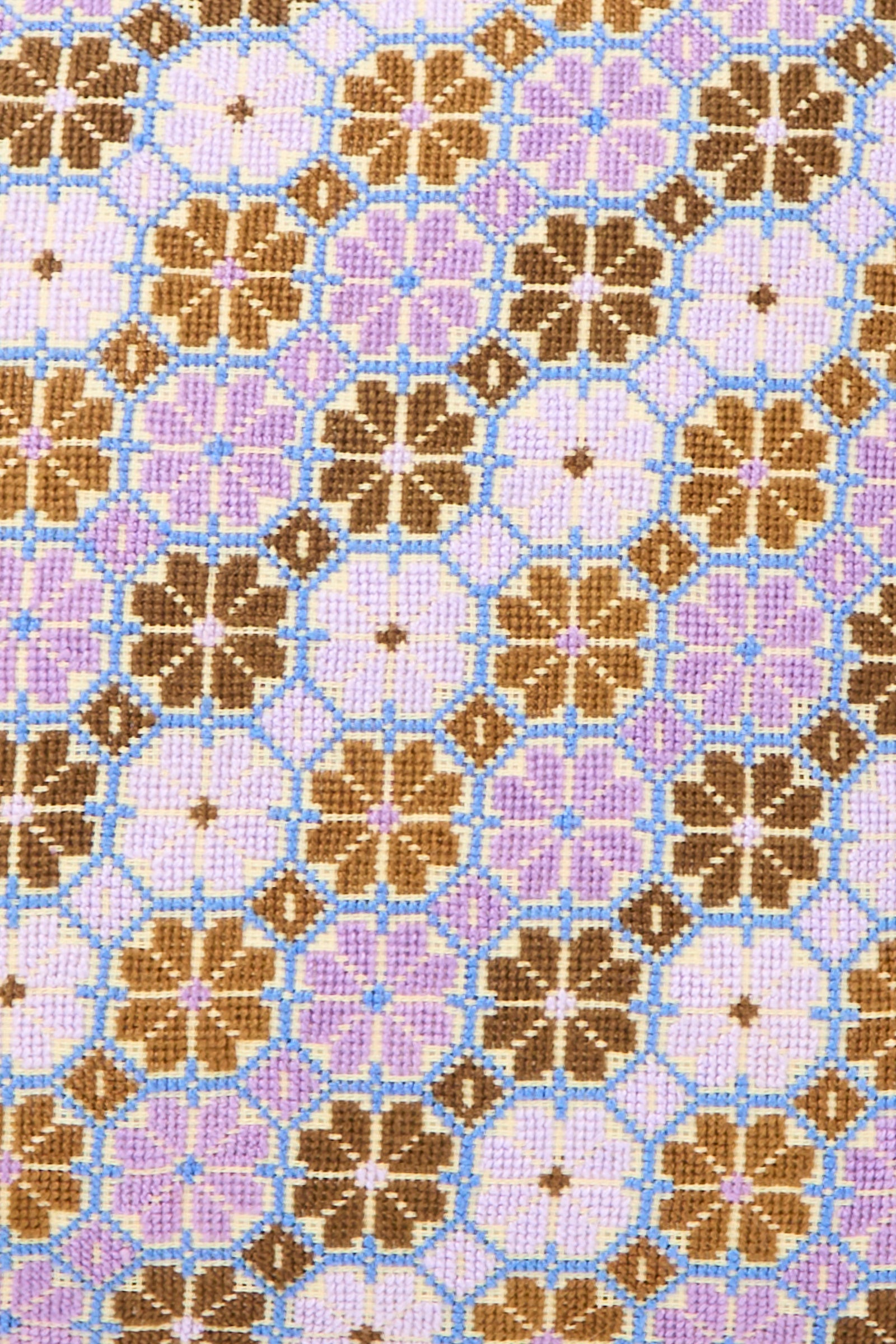 The Damask Rose Hand Embroidered Pillow in Lilac and Cognac by Kissweh features a geometric floral pattern on Libeco Belgian linen, with brown and purple blooms linked by blue lines, reminiscent of cross-stitch embroidery.