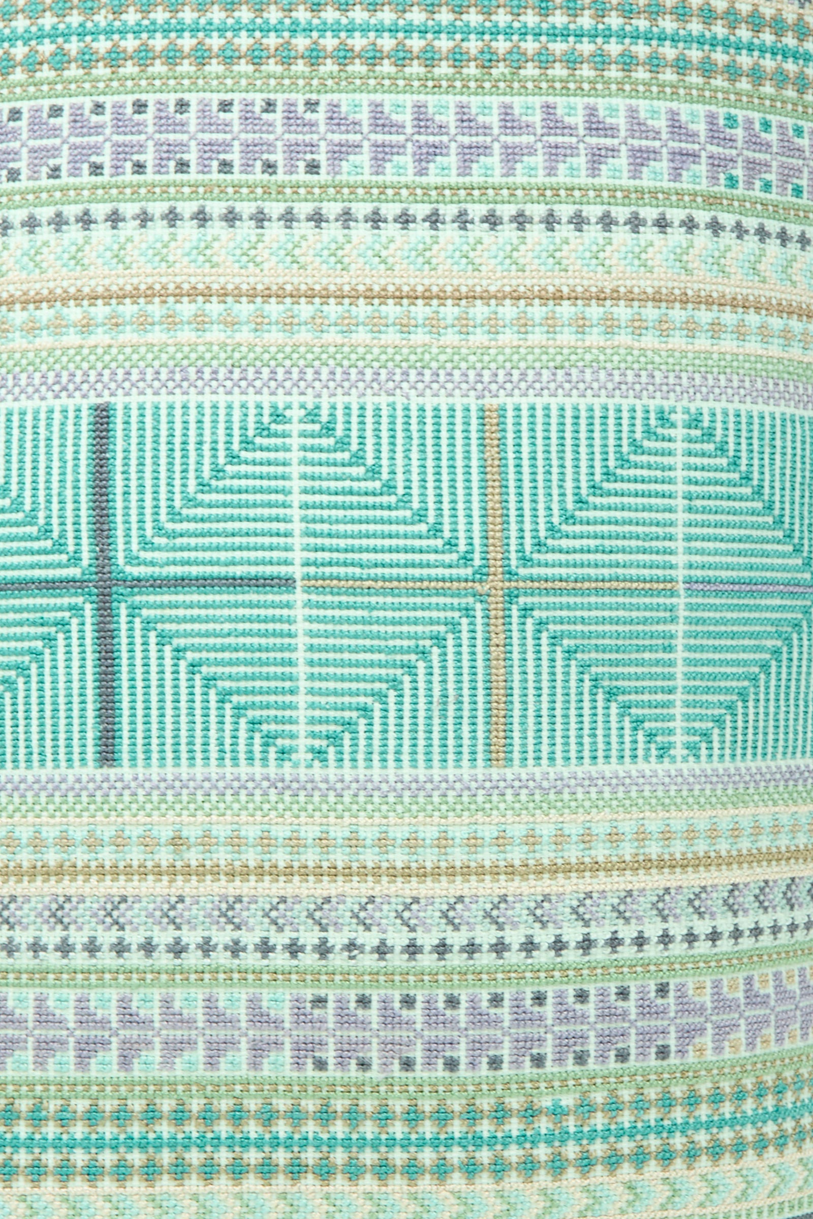 A close-up of the Hanan Hand Embroidered Pillow in Acqua I by Kissweh highlights its Belgian linen and woven geometric patterns in teal, beige, green, and gray tones.