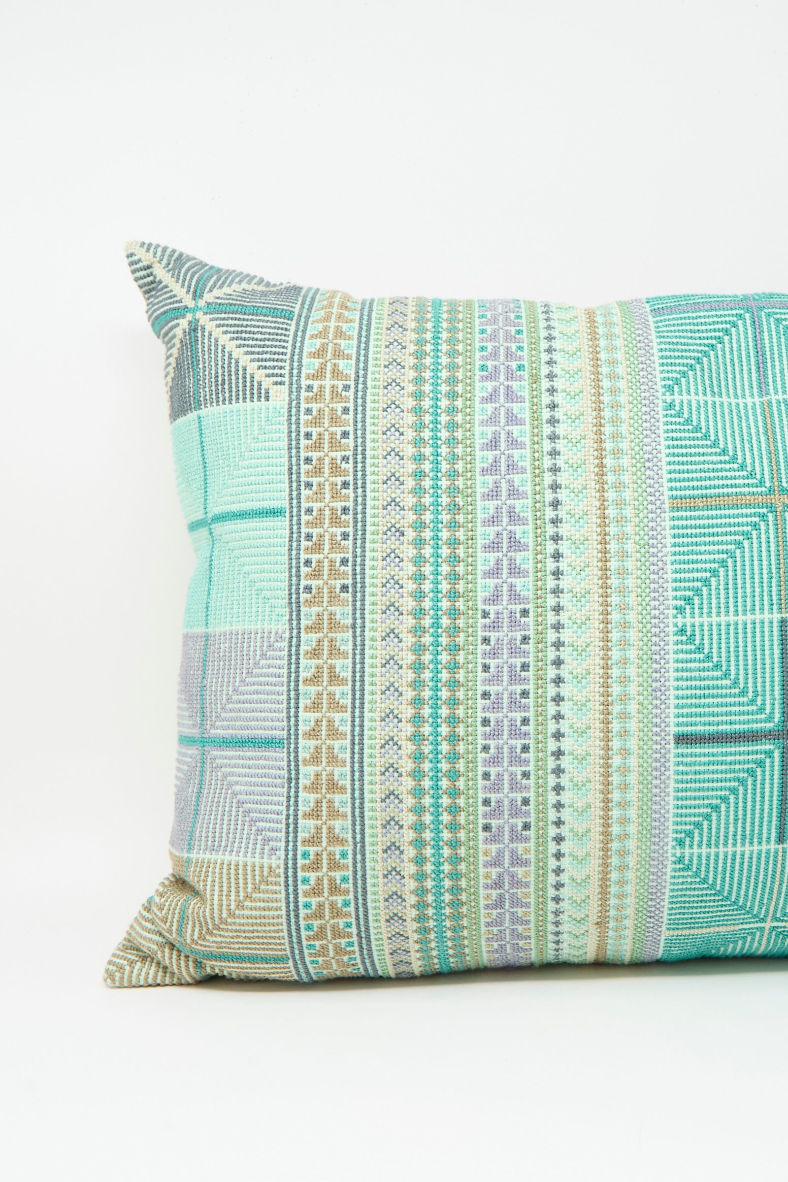 The Kissweh Hanan Hand Embroidered Pillow in Acqua I features geometric patterns in green, blue, grey, and beige on white Belgian linen and comes with a plush down feather insert.
