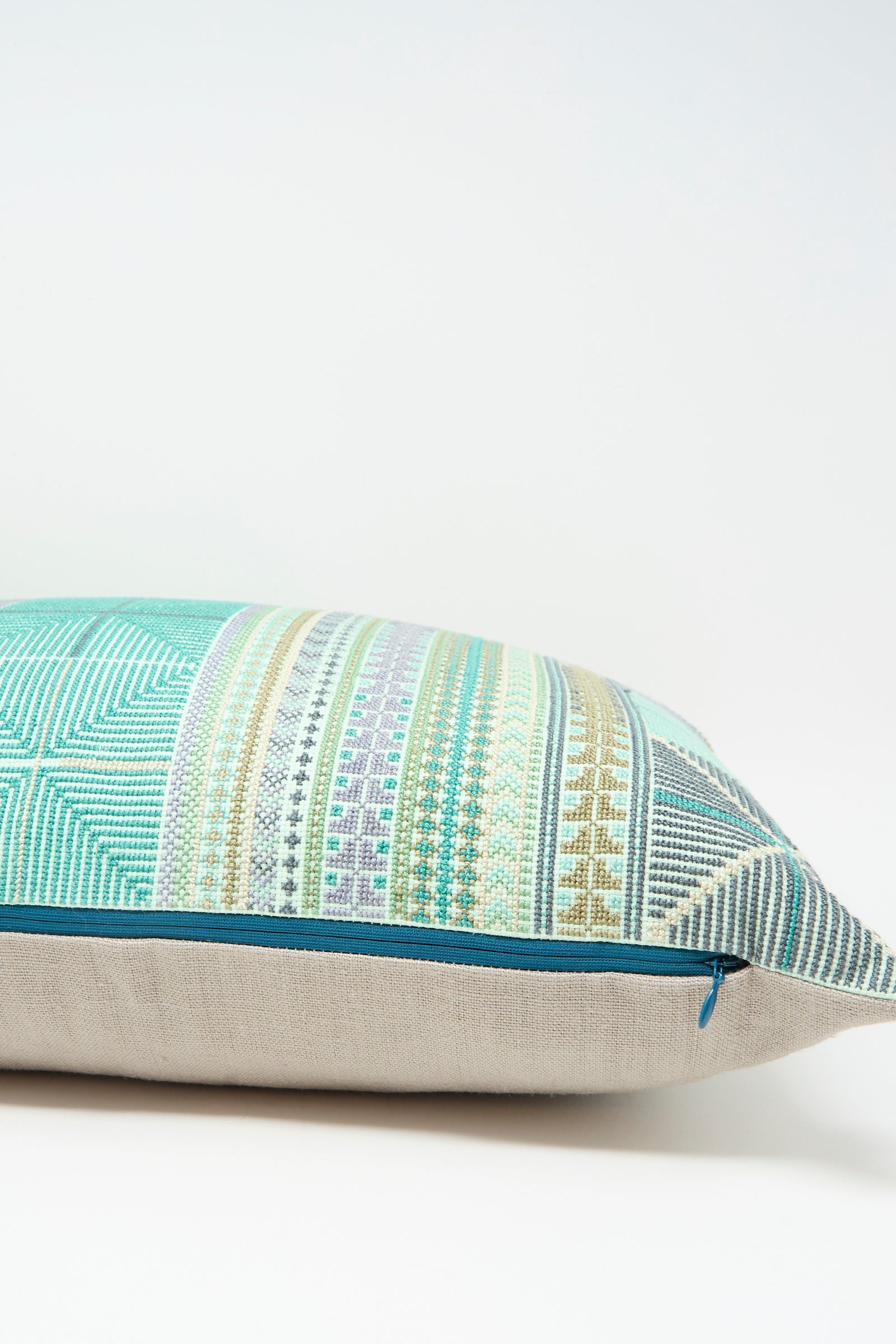 The Hanan Hand Embroidered Pillow in Acqua I by Kissweh features a rectangular Belgian linen design with a geometric multicolored pattern, light beige bottom, blue zipper, and includes a plush down feather insert for comfort.