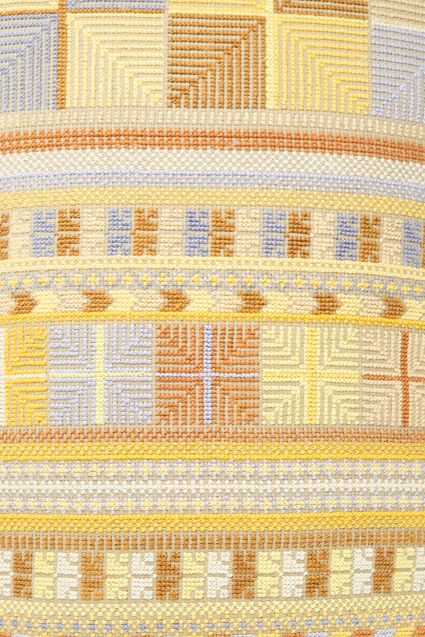 A close-up of the Hanan Hand Embroidered Pillow in Mustard by Kissweh highlights its geometric patterns in beige, yellow, brown, and light blue.
