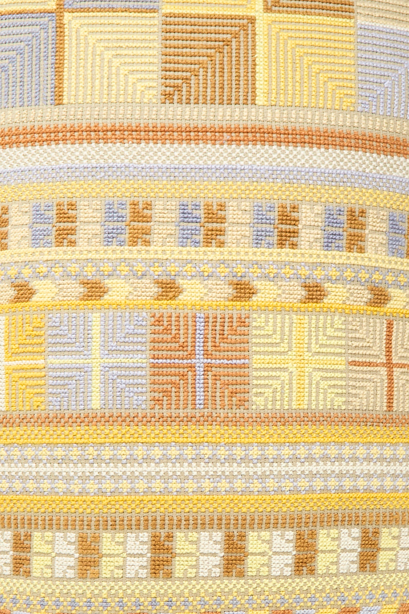 A close-up of the Hanan Hand Embroidered Pillow in Mustard by Kissweh highlights its geometric patterns in beige, yellow, brown, and light blue.
