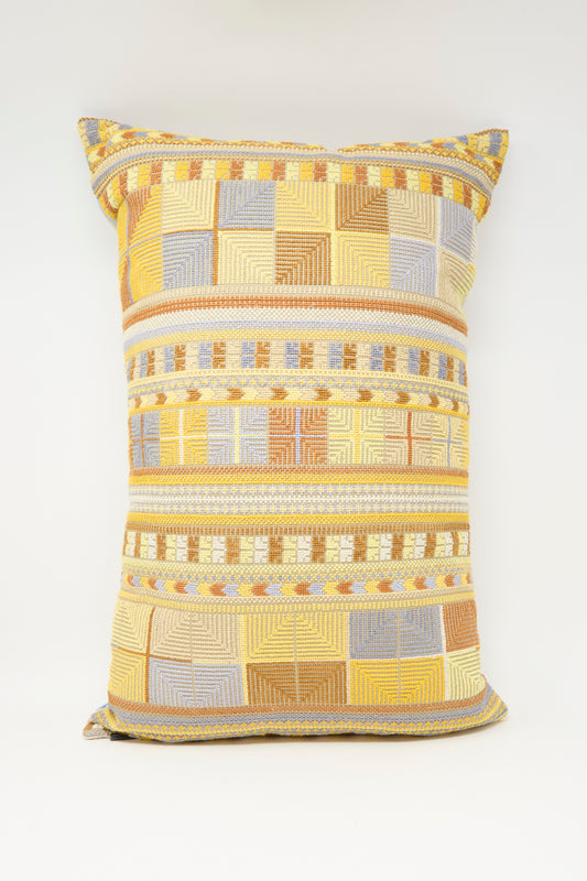 The Hanan Hand Embroidered Pillow in Mustard by Kissweh features a geometric pattern in yellow, gold, beige, and light blue on a white background.