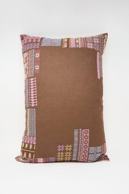 The Kissweh Imm Bushra Hand Embroidered Pillow in Chocolate features patchwork-style patterns in pink, purple, and light blue on a brown background, with a plush down feather insert for comfort.