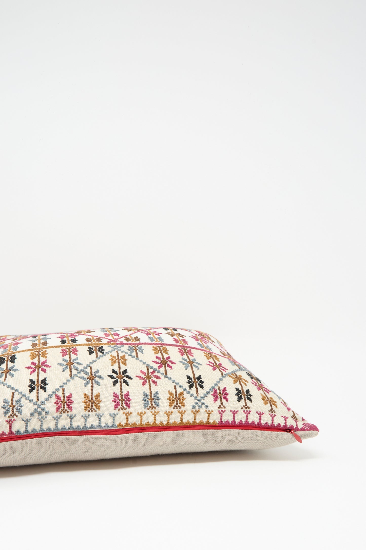 The Kissweh Imm Omar Hand Embroidered Pillow in Beige and Chocolate features multicolored geometric and floral designs on Libeco Belgian linen with a cream background, displayed on a plain white surface.