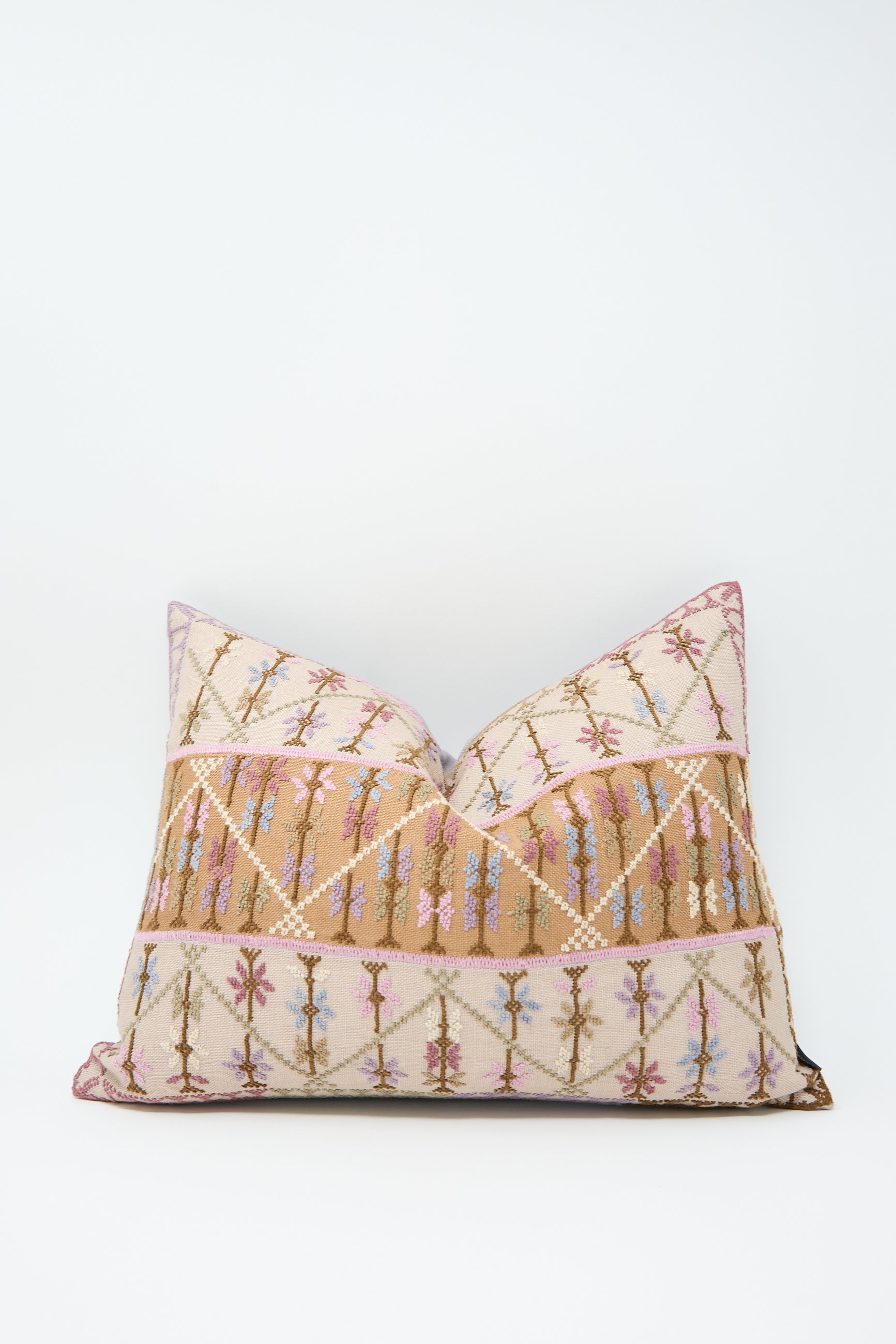 The Kissweh Imm Omar Hand Embroidered Pillow in Beige and Cognac features a multicolored intricate geometric design with diagonal and horizontal lines, predominantly in shades of pink, beige, and blue, against a white Belgian linen background.