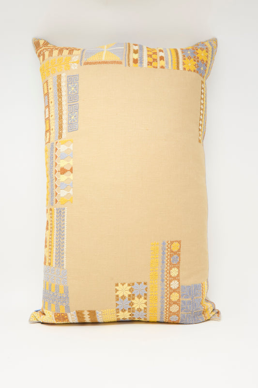 The Kissweh Imm Bushra Hand Embroidered Pillow in Mustard is a rectangular Belgian linen cushion, featuring hand-embroidered patchwork in yellow, gold, and light blue at the corners on a plain white background.