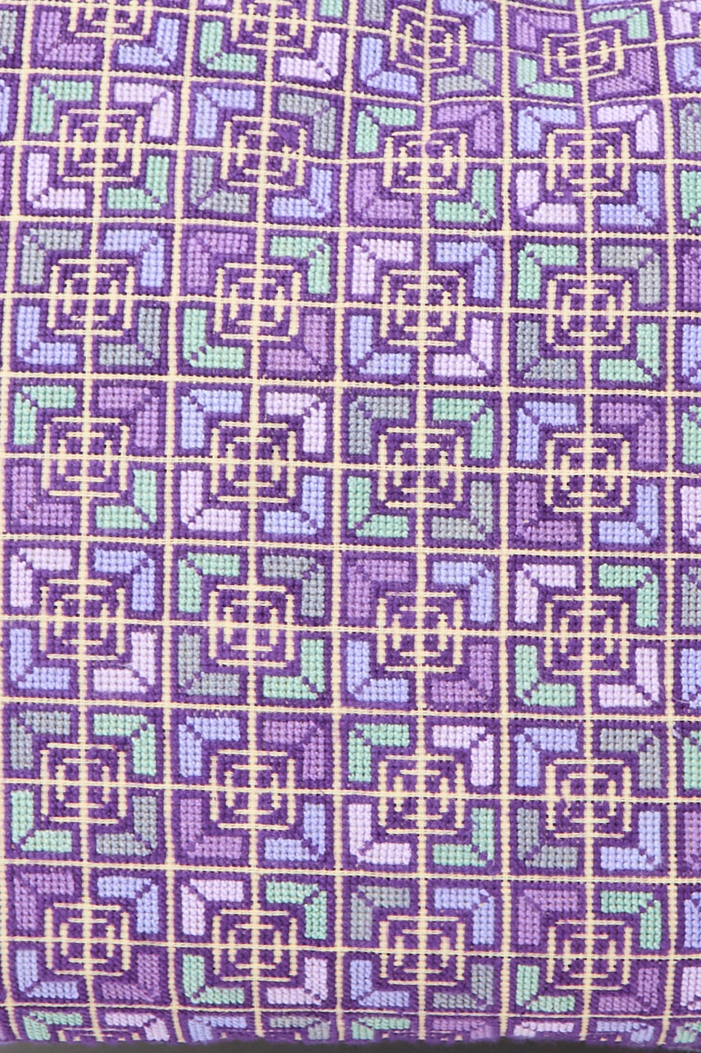 Close-up of the Kissweh Rana Hand Embroidered Pillow in Lilac and Purple I, featuring a geometric grid pattern in purple, green, and blue squares and lines—perfect for adding a stylish accent to your décor.