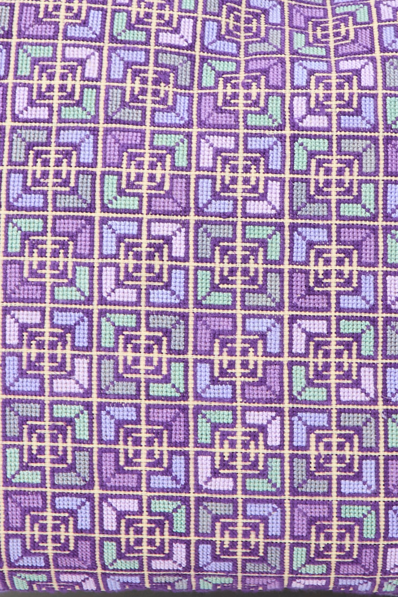 Close-up of the Kissweh Rana Hand Embroidered Pillow in Lilac and Purple I, featuring a geometric grid pattern in purple, green, and blue squares and lines—perfect for adding a stylish accent to your décor.