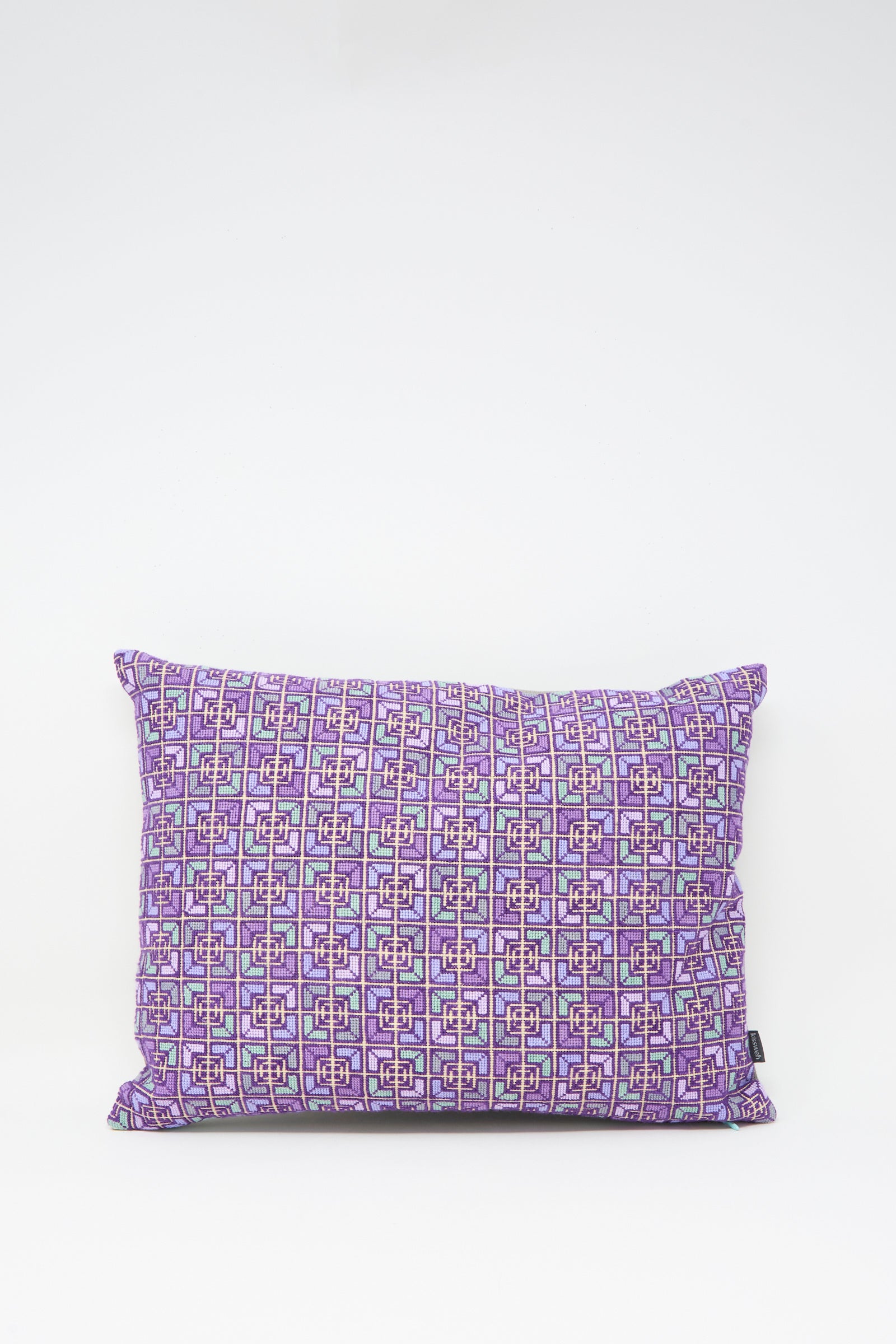 The Kissweh Rana Hand Embroidered Pillow in Lilac and Purple I features a rectangular design with a purple geometric pattern on white Belgian linen.