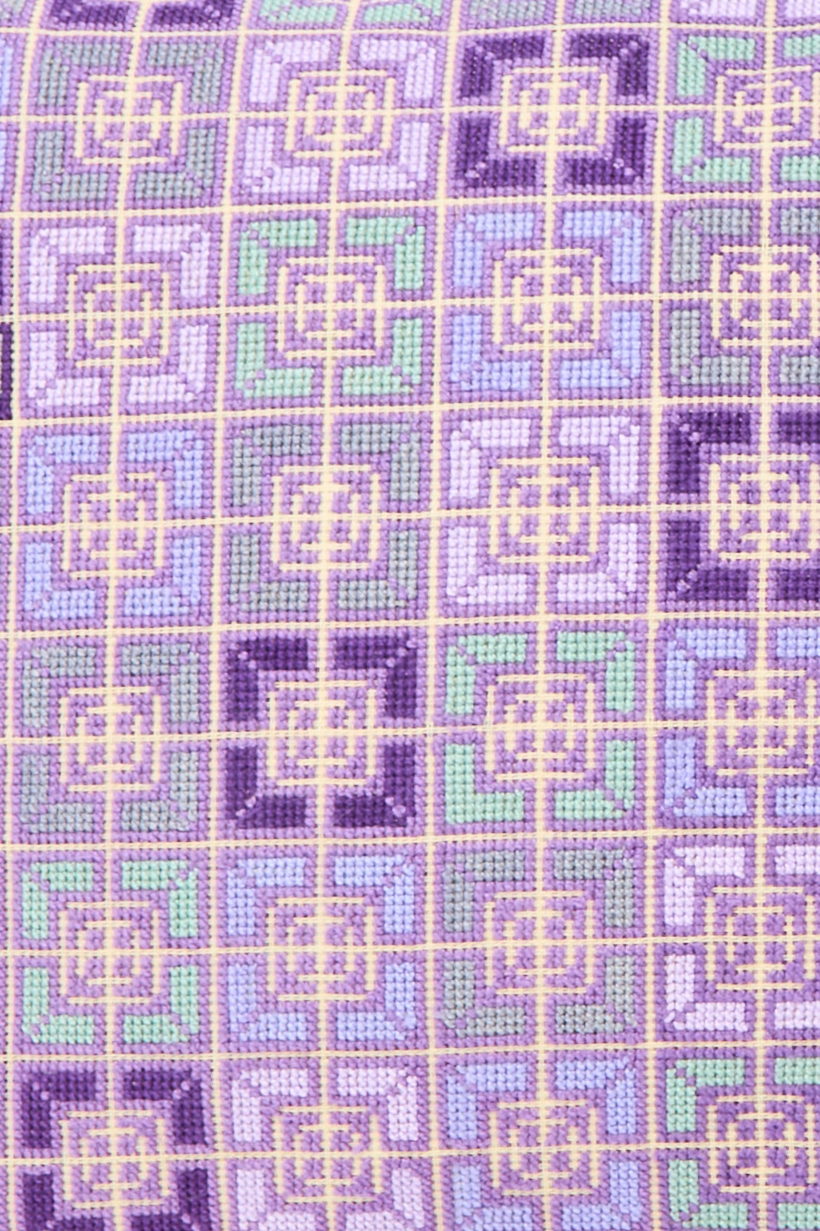 The Rana Hand Embroidered Pillow in Lilac and Purple II by Kissweh features a geometric pattern in purple, lavender, green, and yellow on Belgian linen with a plush down feather insert.