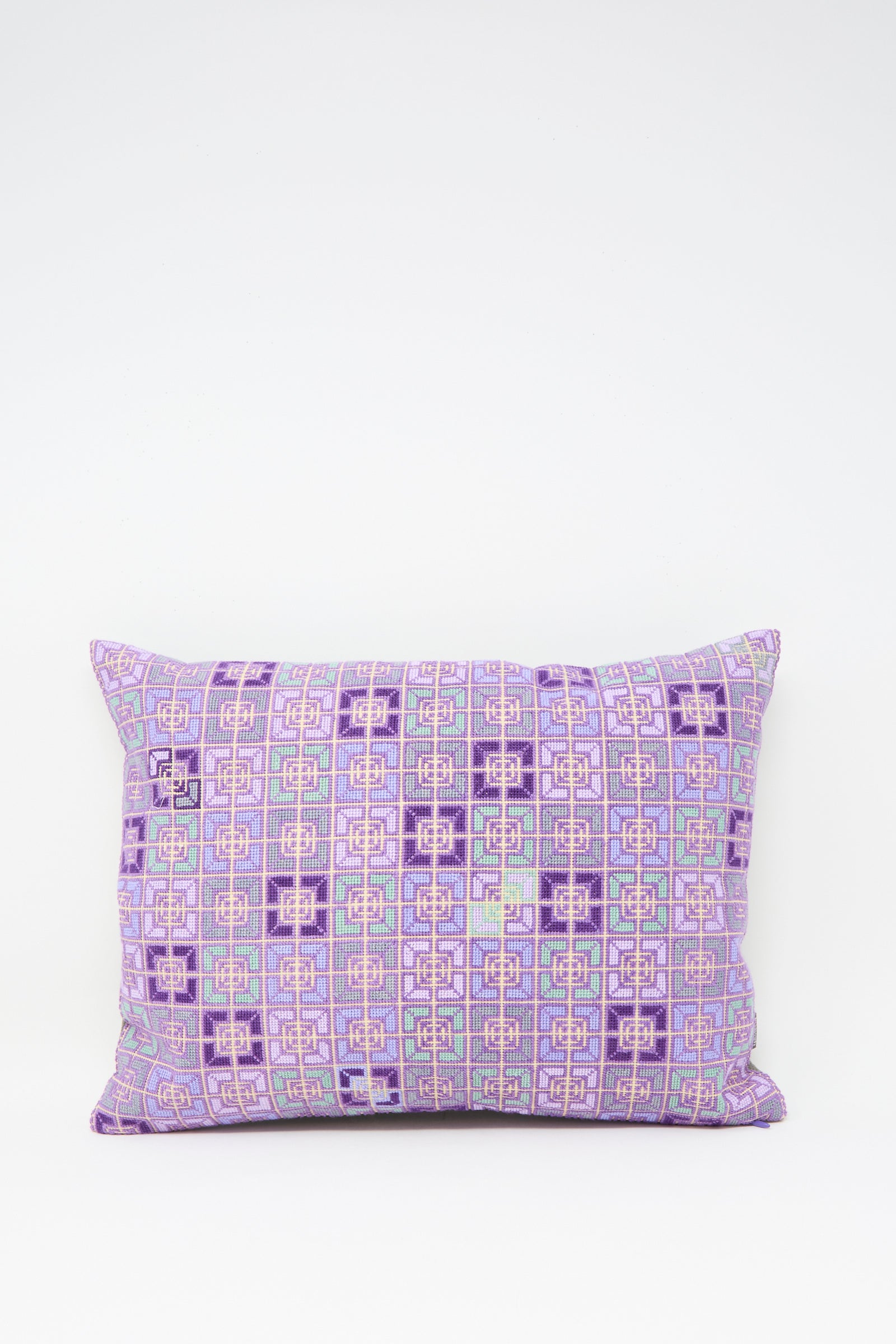 The Kissweh Rana Hand Embroidered Pillow in Lilac and Purple II features a geometric pattern in shades of purple, lilac, pink, and light blue, displayed against a plain white background.
