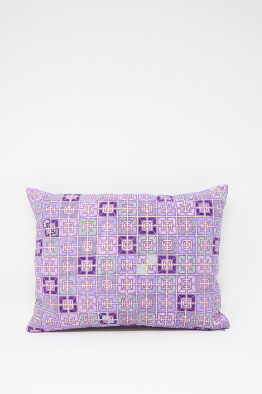 The Kissweh Rana Hand Embroidered Pillow in Lilac and Purple II features a geometric pattern in shades of purple, lilac, pink, and light blue, displayed against a plain white background.