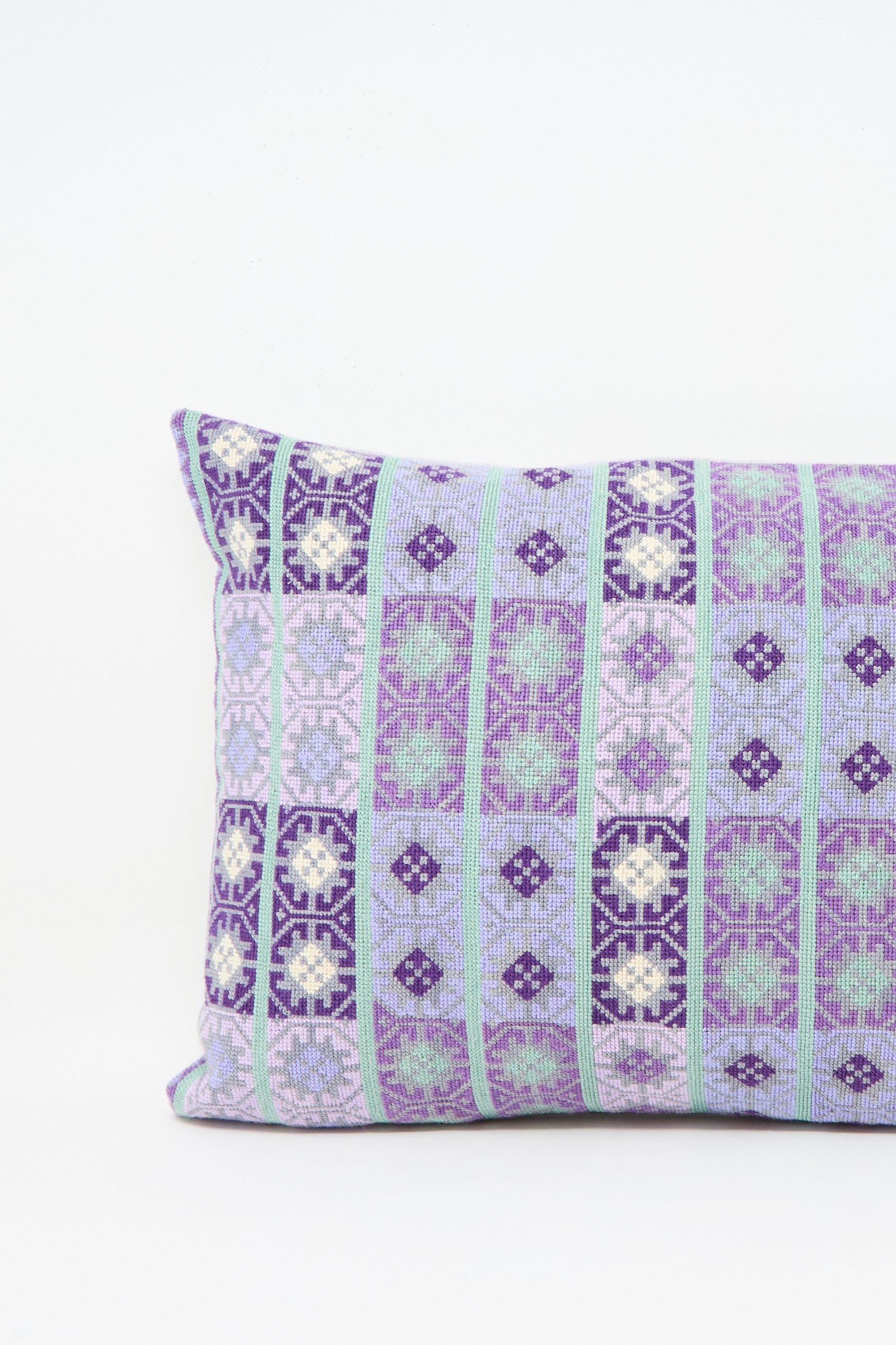 The Wafa'a Hand Embroidered Pillow in Lilac by Kissweh features a geometric pattern in purple, light blue, and white on a plain white background, with a plush down feather insert for extra comfort.