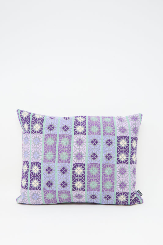 The Kissweh Wafa'a Hand Embroidered Pillow in Lilac features a rectangular shape with geometric purple, blue, and white embroidery on a crisp white background. Comes with a plush down feather insert for extra comfort.