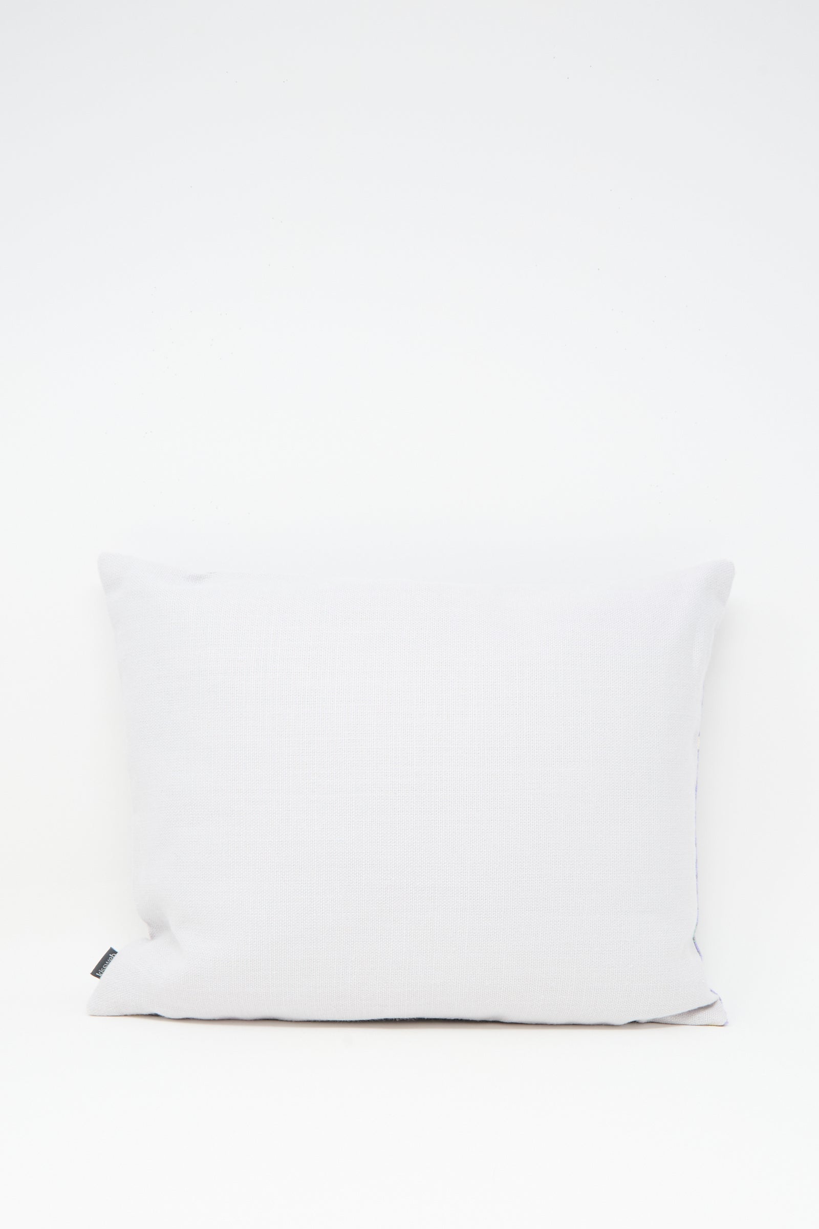 The Wafa'a Hand Embroidered Pillow in Lilac by Kissweh features intricate embroidery and a subtle lilac hue, shown here with a down feather insert and a small black tag on the left side against a white background.