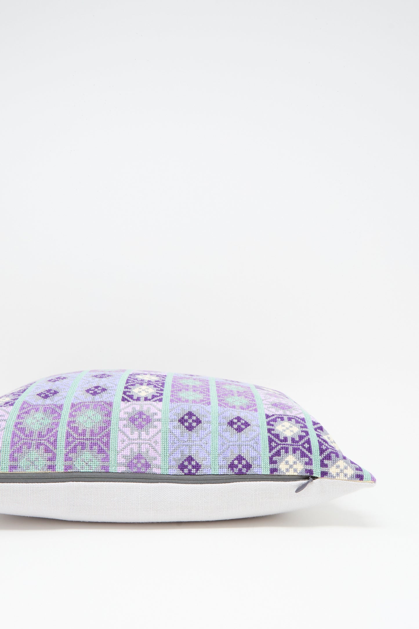 The Wafa'a Hand Embroidered Pillow in Lilac by Kissweh features a geometric blue, purple, and white design with a plush down feather insert, shown on a plain white background.