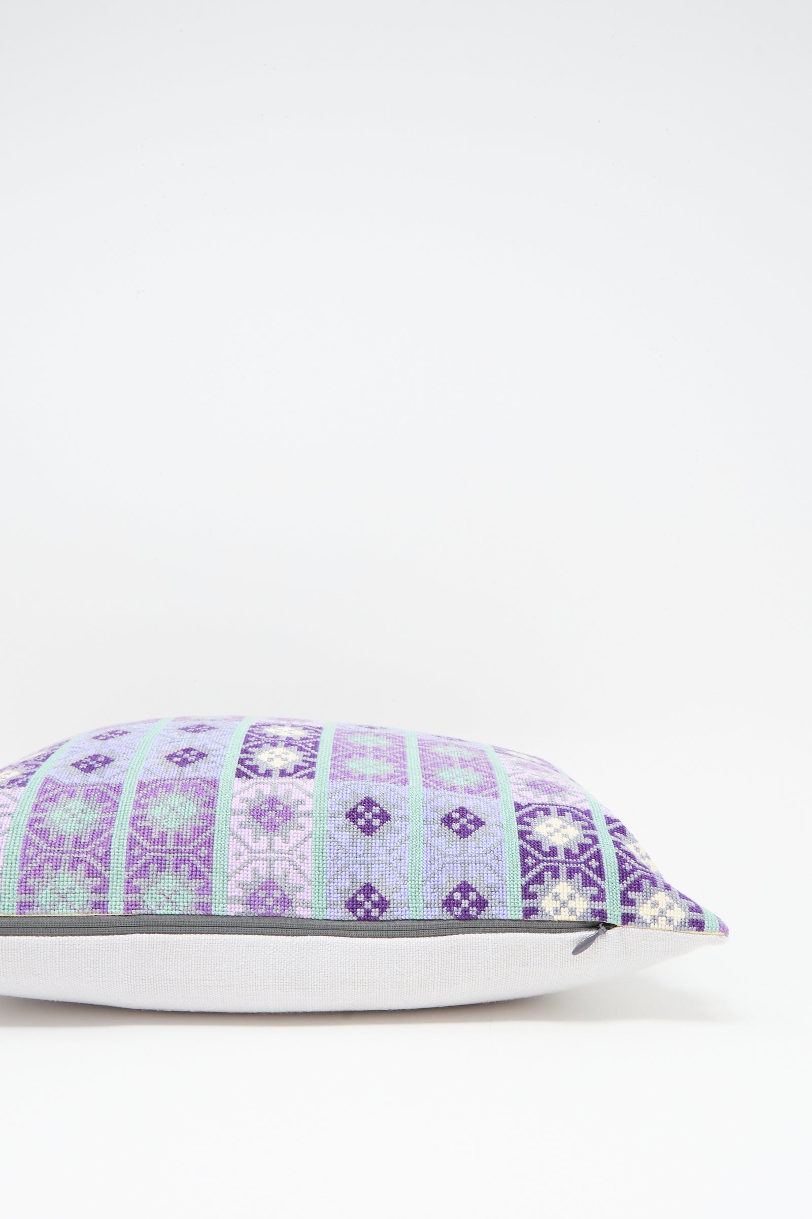 The Wafa'a Hand Embroidered Pillow in Lilac by Kissweh features a geometric blue, purple, and white design with a plush down feather insert, shown on a plain white background.