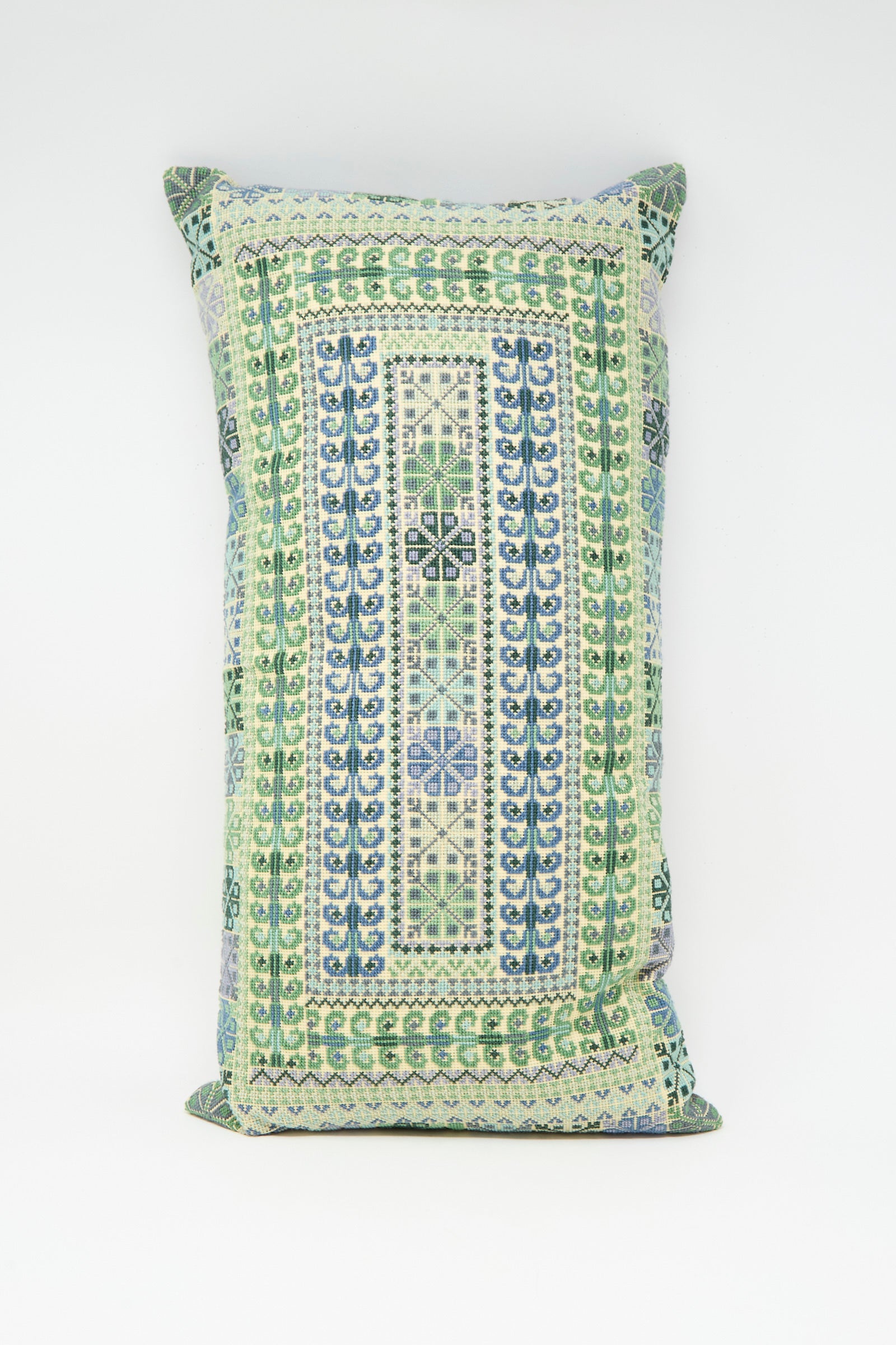 The Yasmin Hand Embroidered Pillow in Olive by Kissweh features intricate blue and green geometric embroidery on premium Belgian linen, beautifully displayed against a plain white surface.