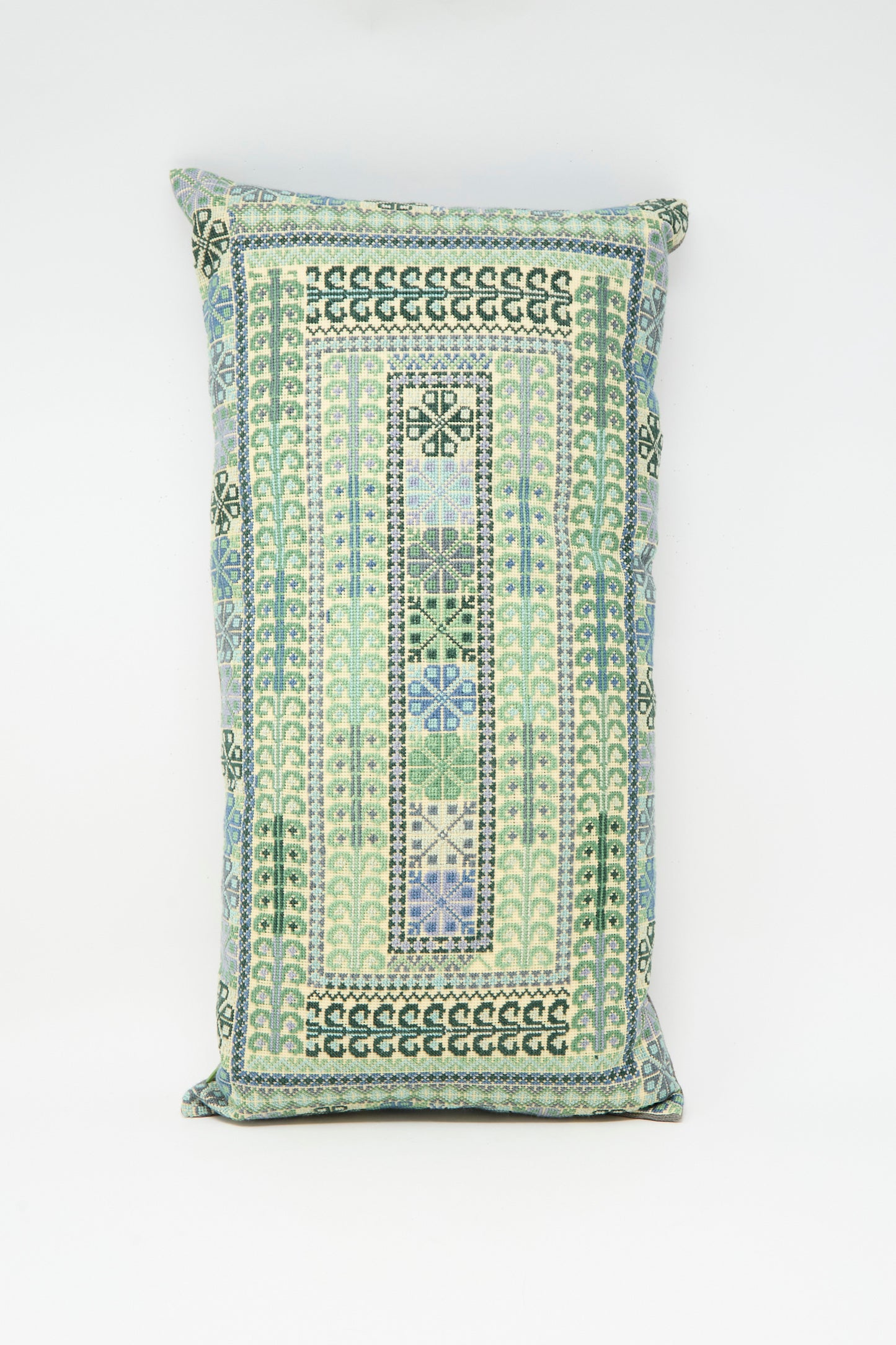 The Yasmin Hand Embroidered Pillow in Olive and Slate by Kissweh features geometric patterns in blue, green, and cream on white Belgian linen.