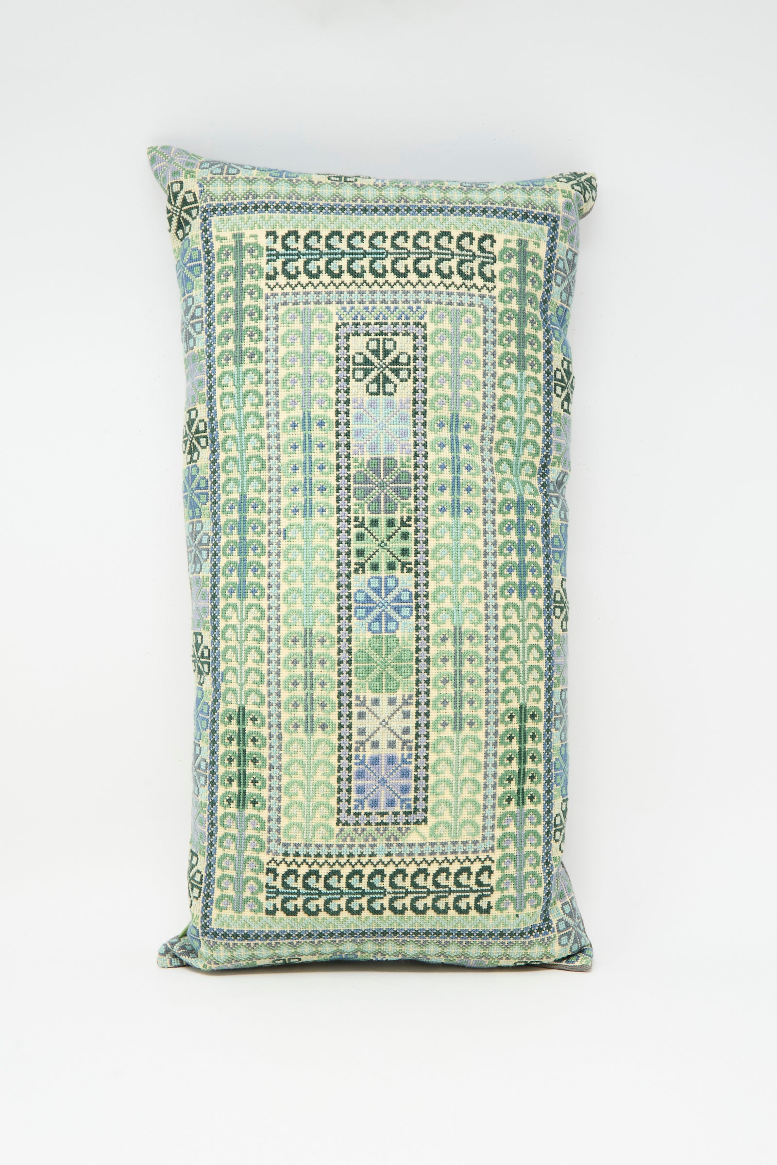 The Yasmin Hand Embroidered Pillow in Olive and Slate by Kissweh features geometric patterns in blue, green, and cream on white Belgian linen.